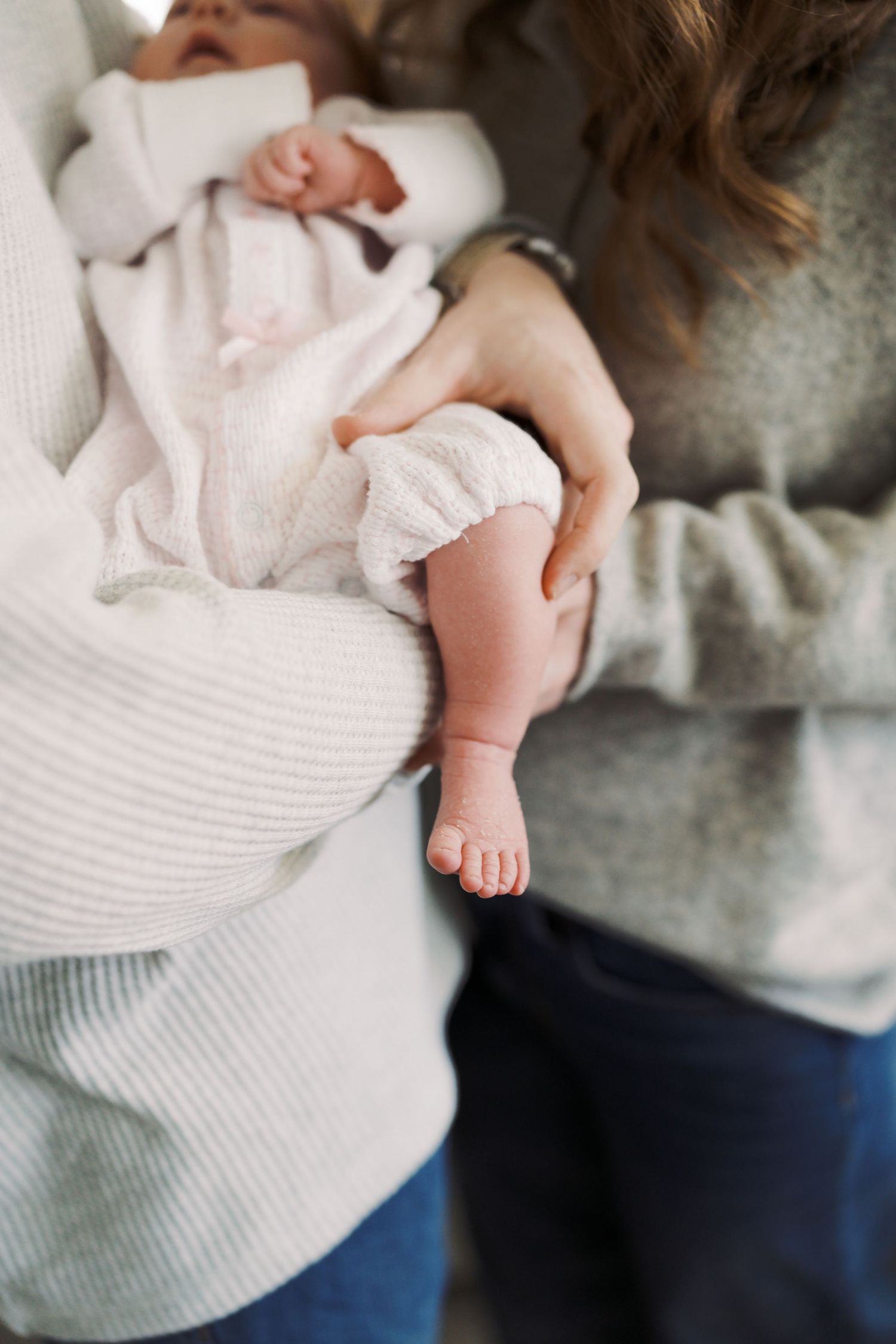 A close-up view of a baby's feet being held by a parent's hands.