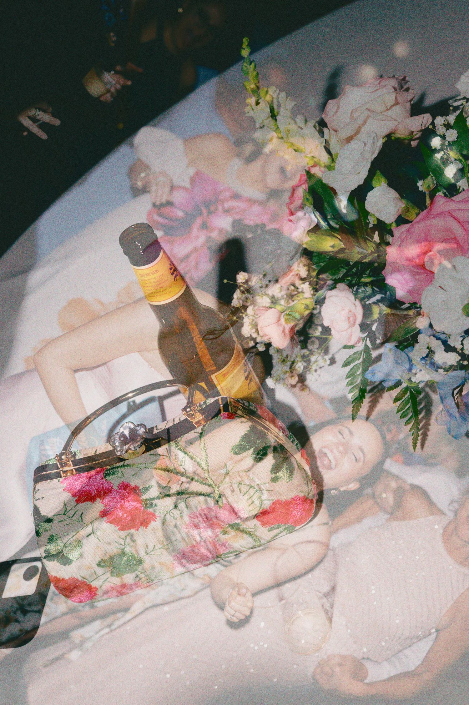 Double exposure photo of a woman lying down with a beer bottle, floral clutch bag, and pink flower bouquet.