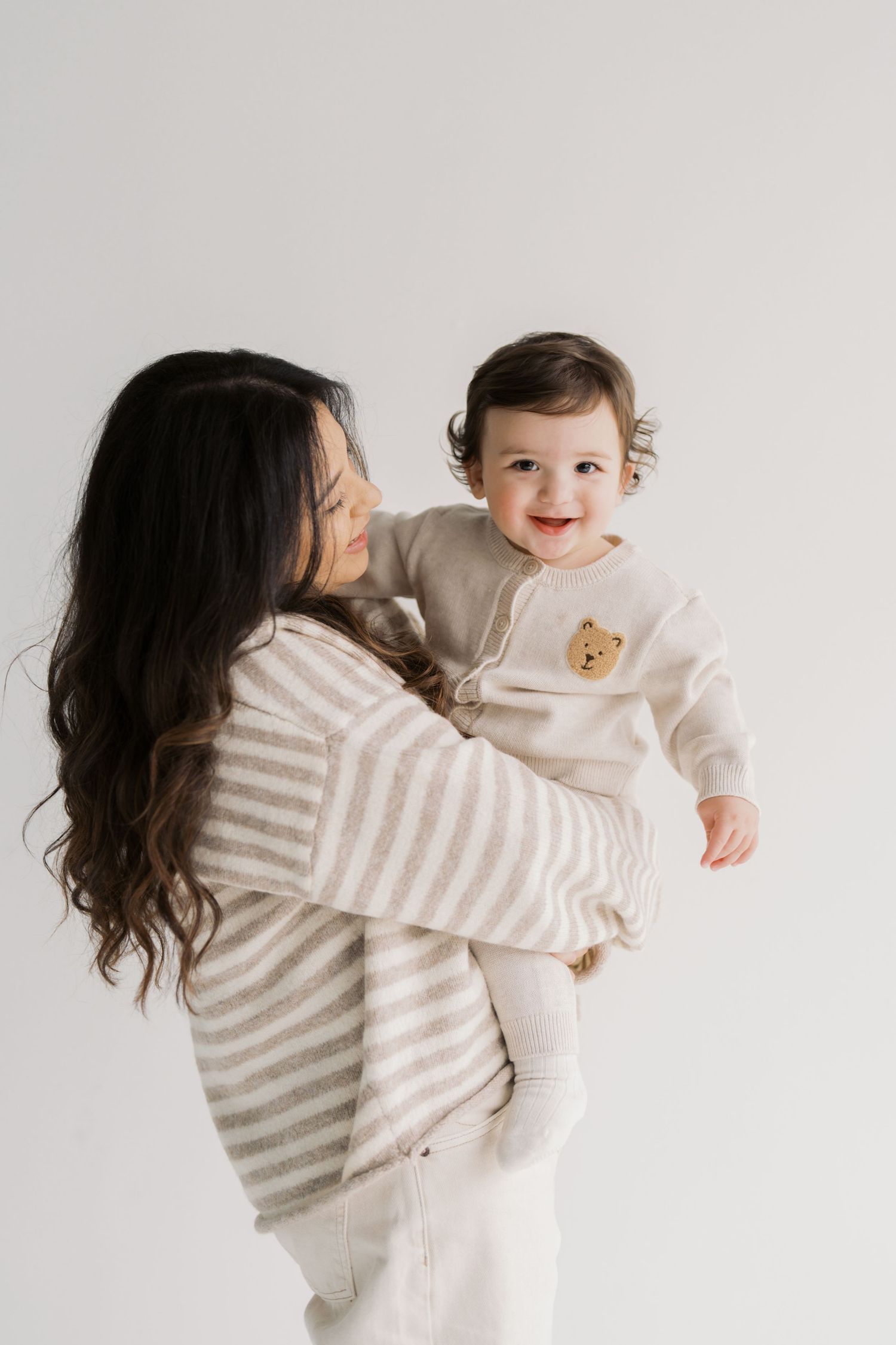 A woman holding a smiling baby in her arms.