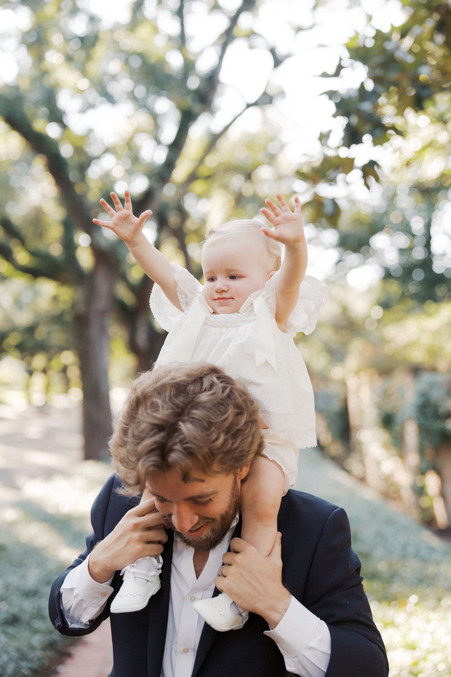 A sequence of photos showing a person in a suit holding a baby in white against a sunlit outdoor background.