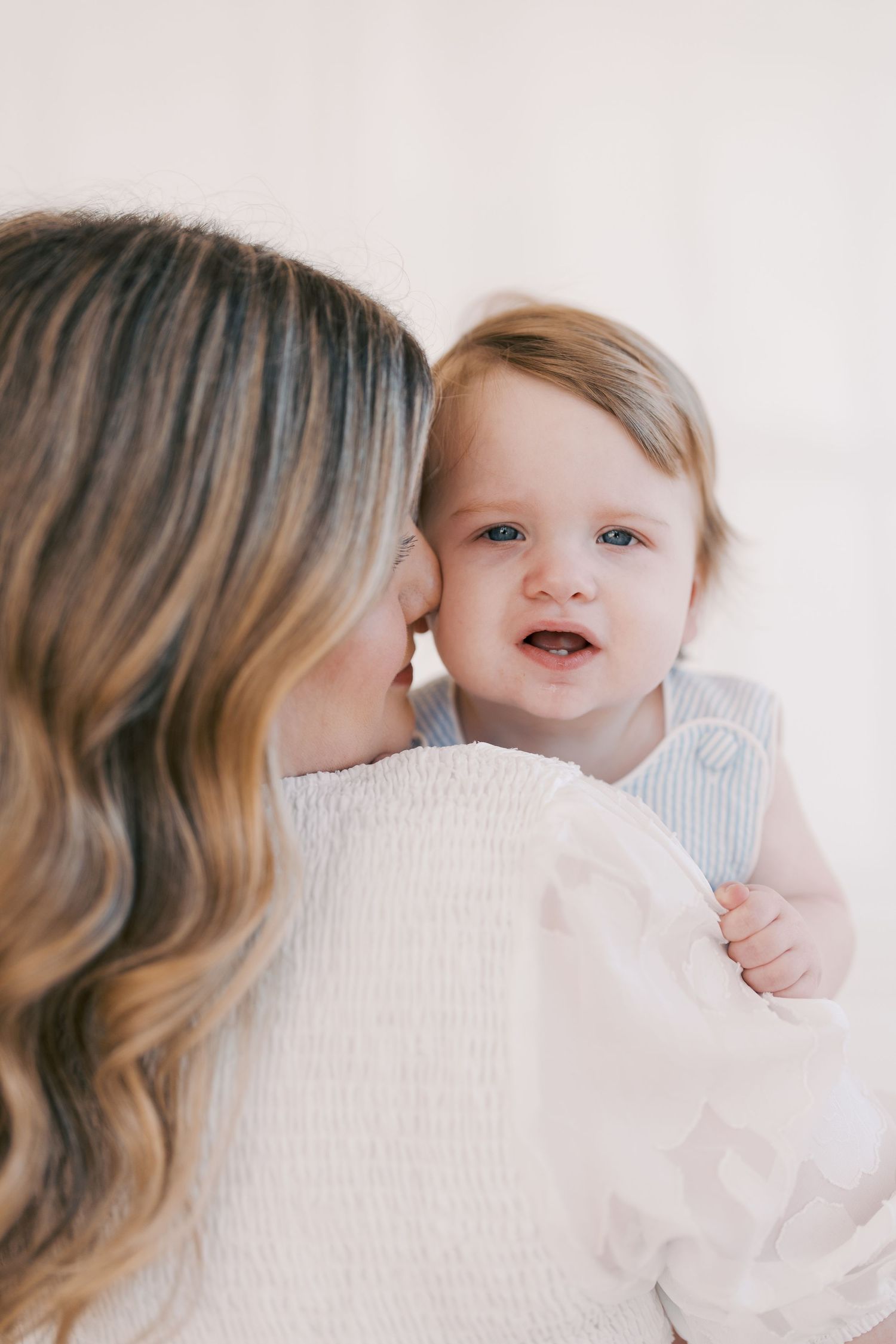 Tender moment between parent and baby in white knit clothing.