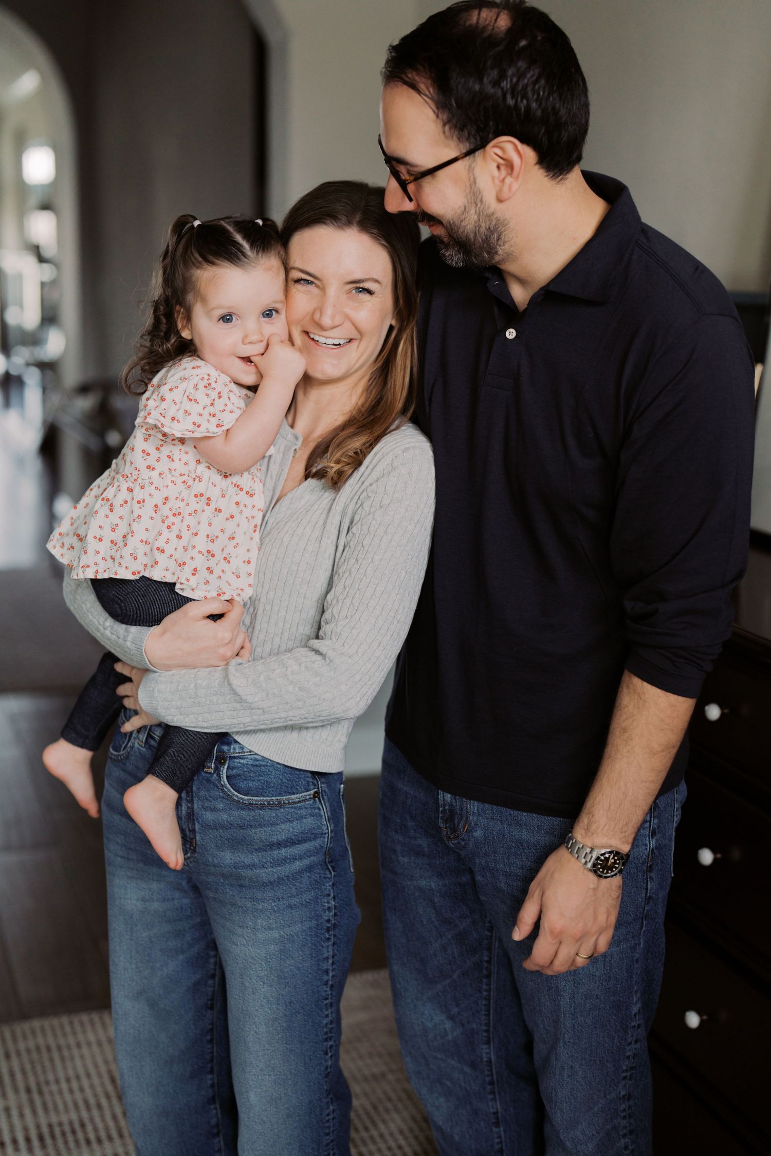 A man, woman, and young girl are standing together and smiling happily.