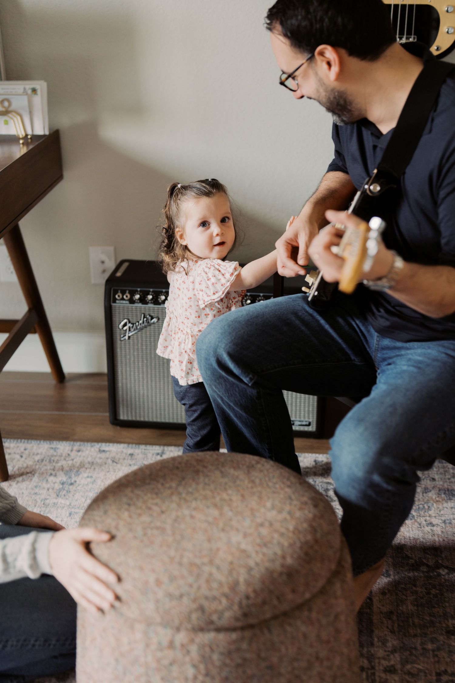 A man is sitting on the floor with a young girl, playing with a musical instrument.
