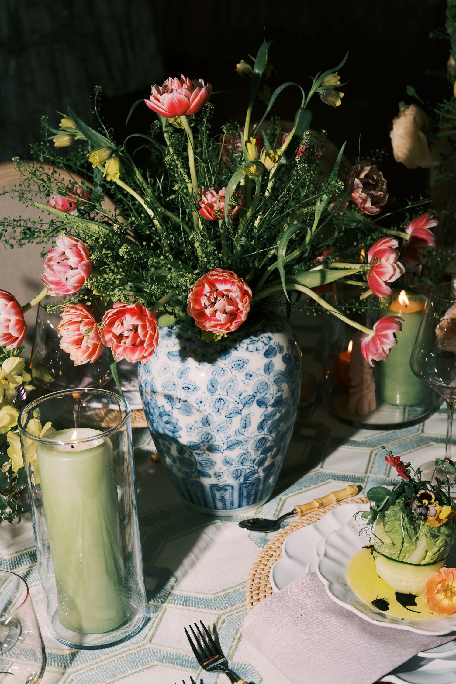 Pink peonies arranged in a blue and white chinoiserie vase with elegant table settings.