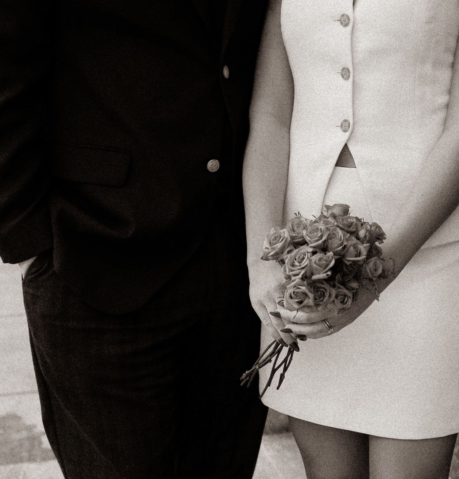 Black and white close-up of a bride holding a rose bouquet beside a groom in a classic wedding photo.