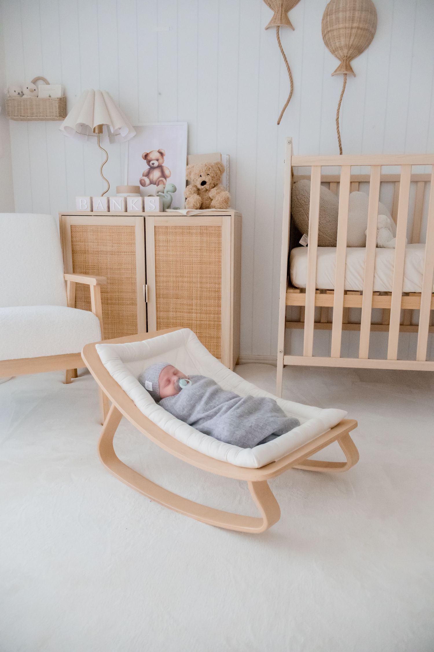 Modern wooden baby rocker with light gray cushioning shown from different angles in a minimalist nursery setting.