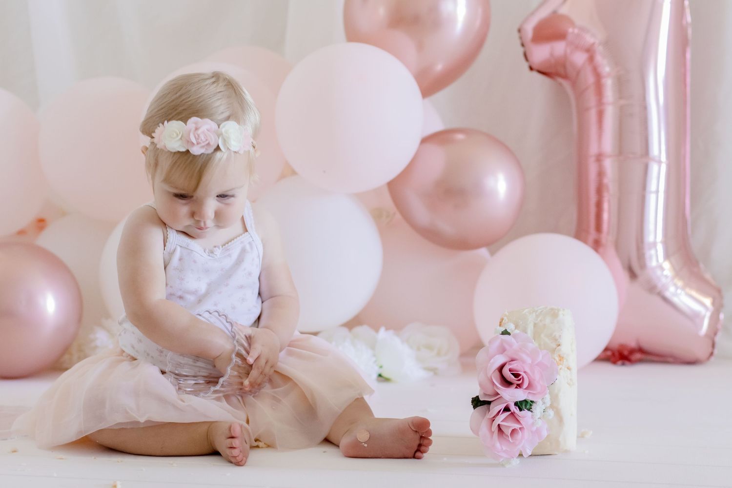 Soft pink birthday photoshoot featuring tulle dress and rose decorations.