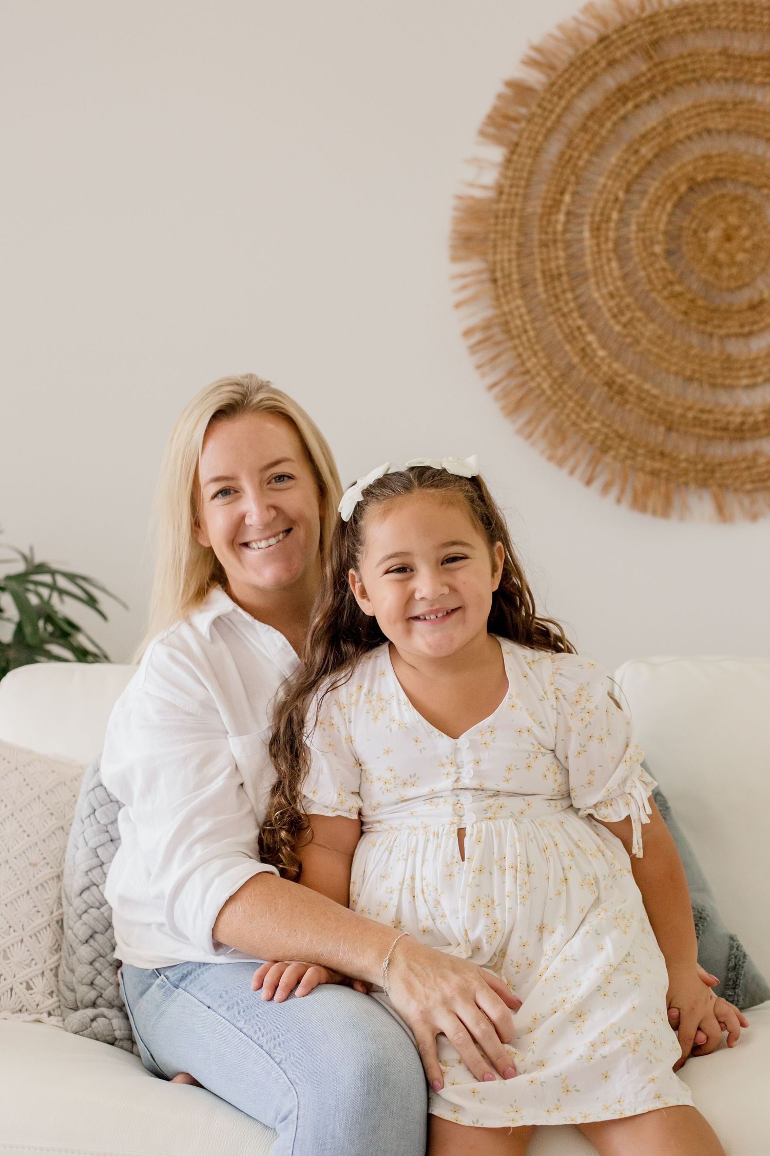 Sweet moment shared on white couch beneath circular woven wall art.