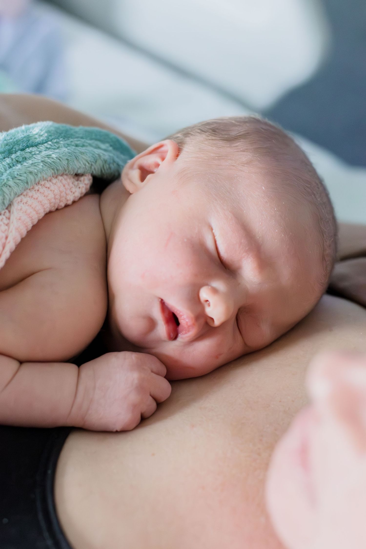 Newborn baby sleeping peacefully on mother's chest during skin-to-skin contact after birth.