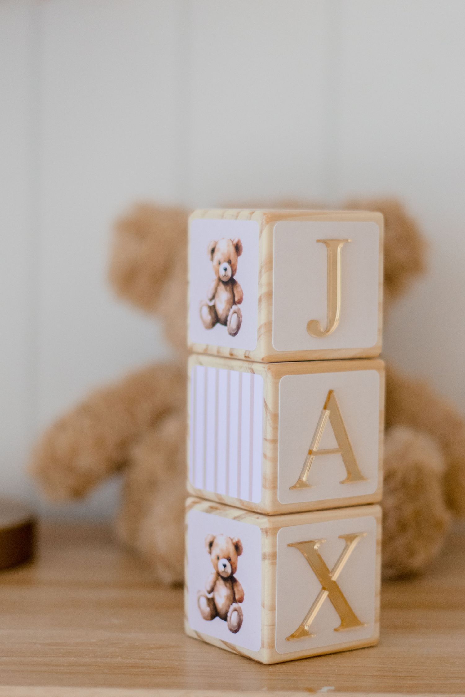 Decorative baby blocks with bears and letters J, A, X displayed on a wooden surface.