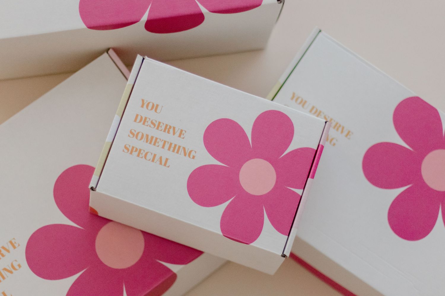 White business cards with pink floral designs and gold text arranged in a minimalist layout on a light surface.
