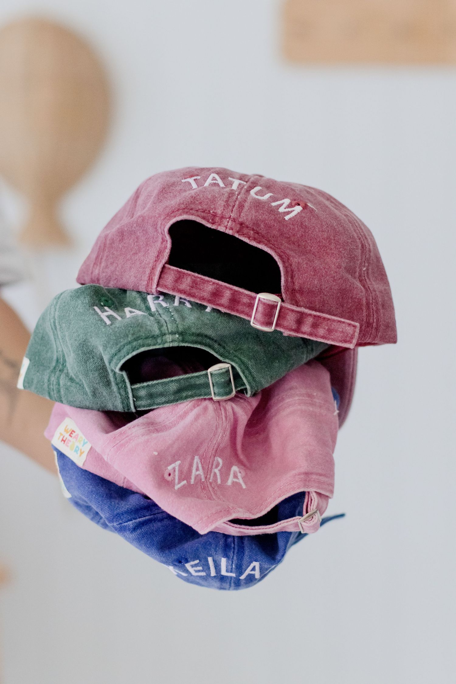 Stack of vintage-style baseball caps in pink, green, and blue colors.
