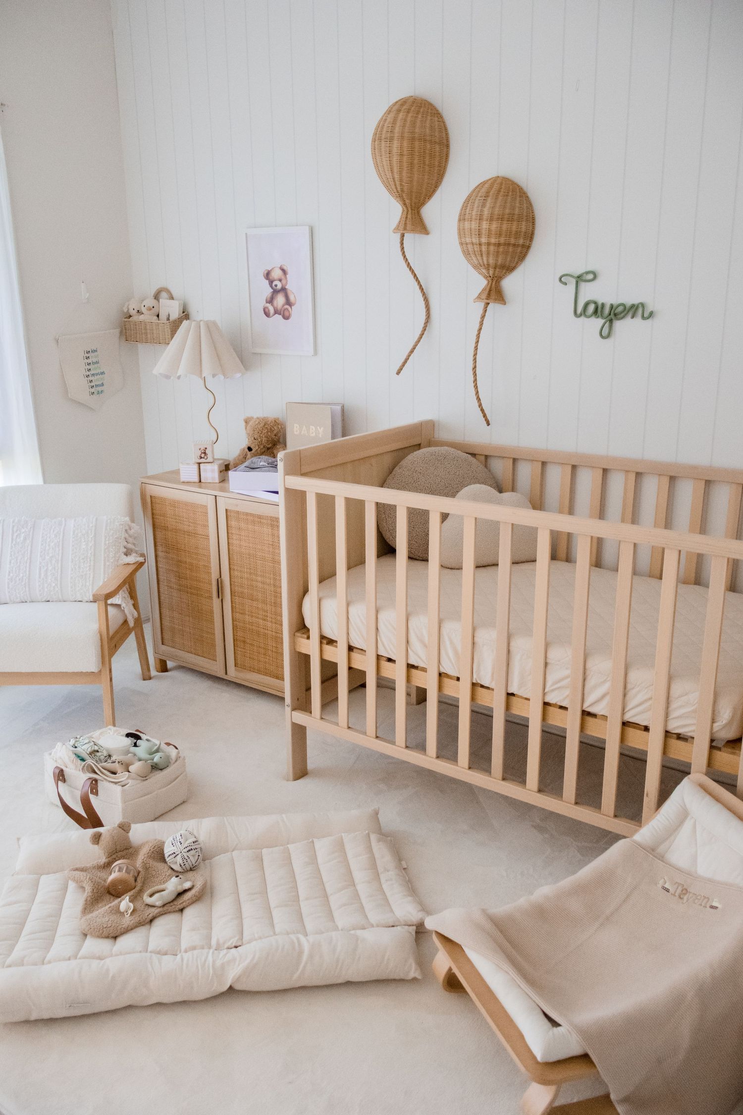 Serene nursery room with wooden crib, rattan decor, and neutral color palette featuring hot air balloon decorations.
