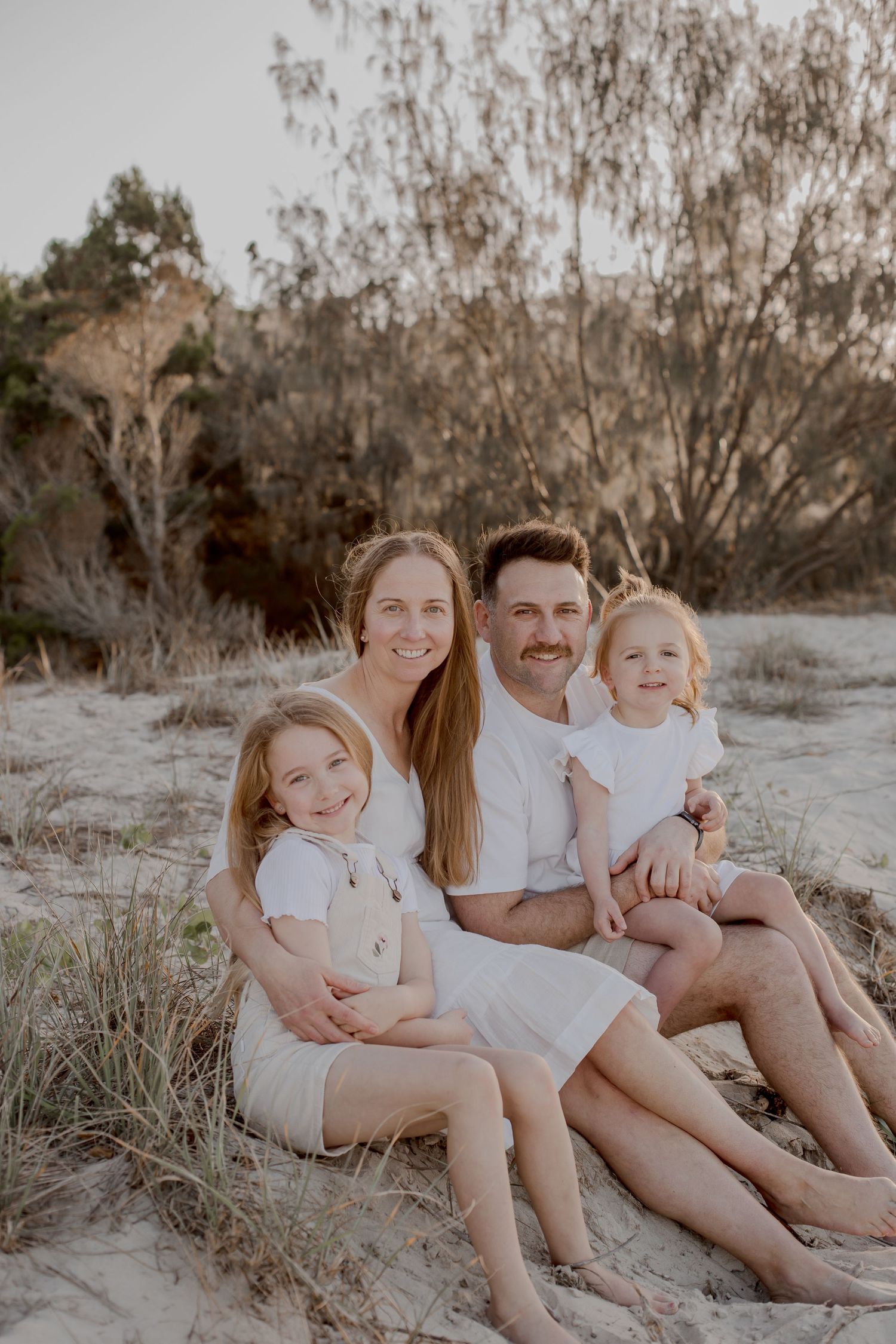 Family portrait on sandy beach during golden hour.