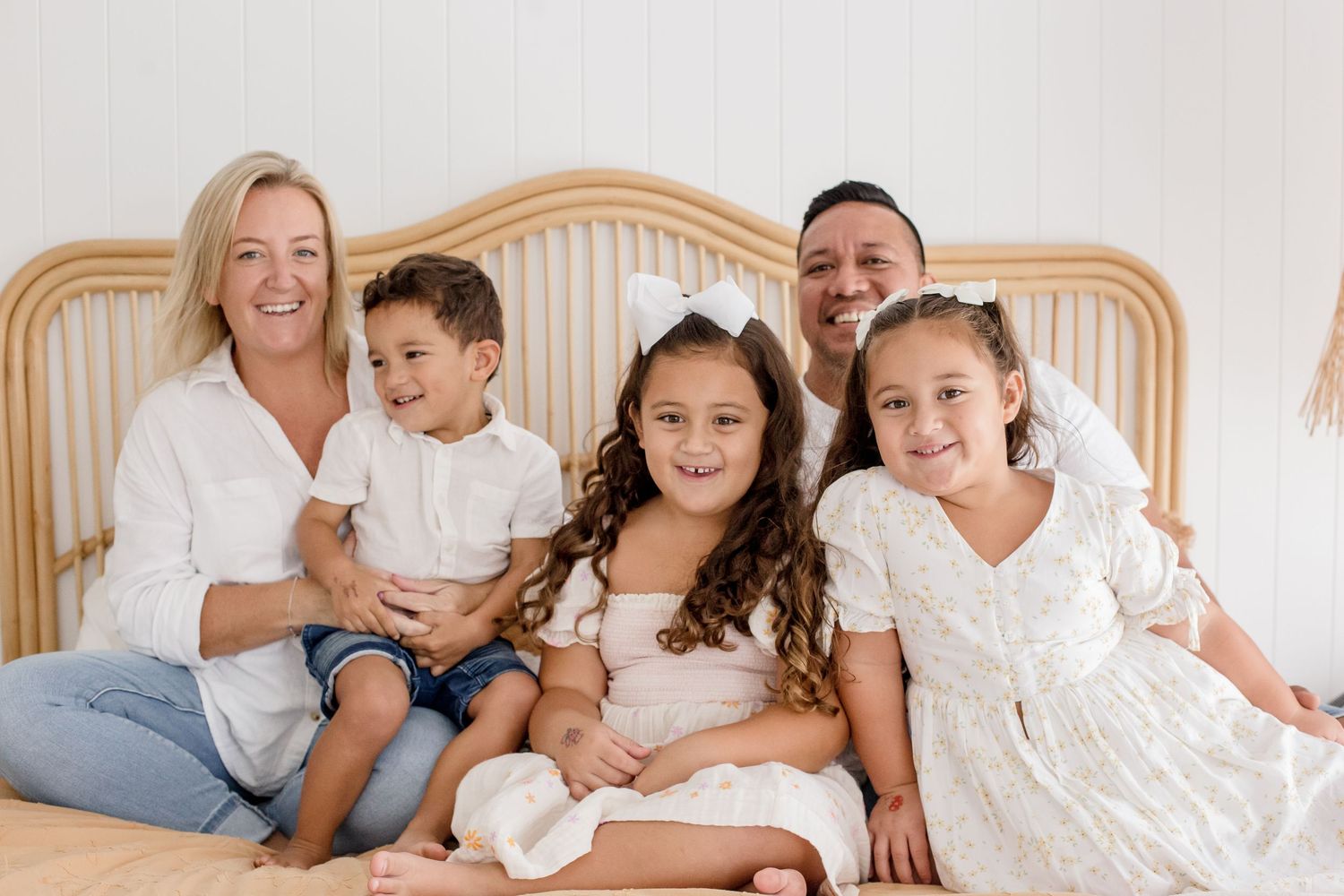 Family shares joyful moment together on elegant wooden bed with light decor.