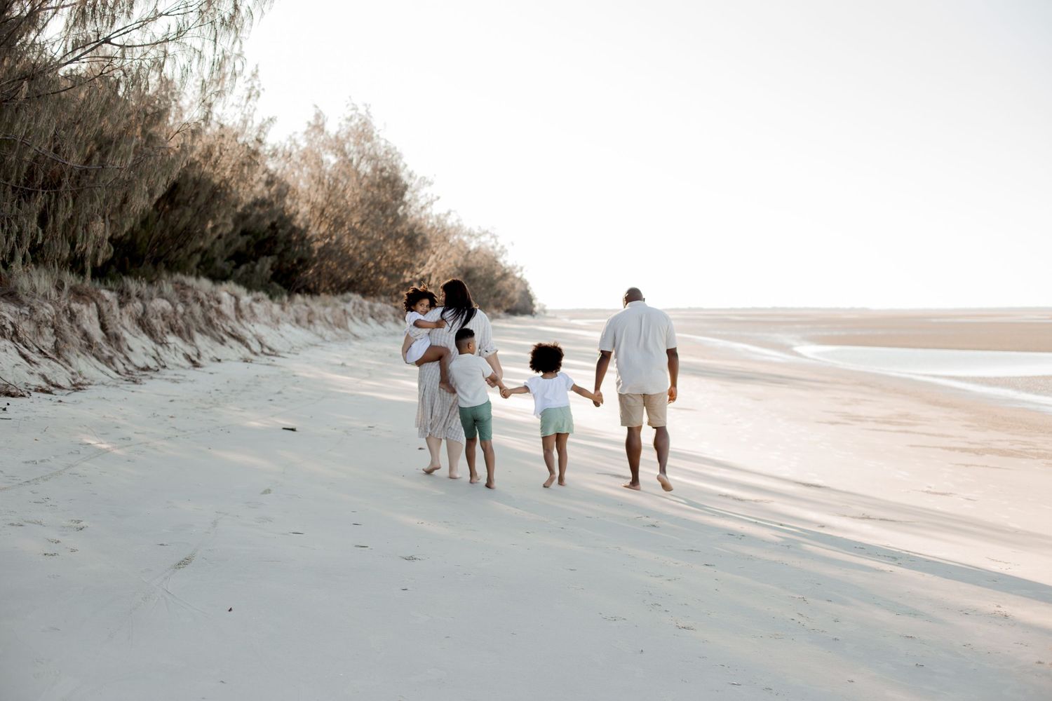 Family walking together along a serene beach at sunset.