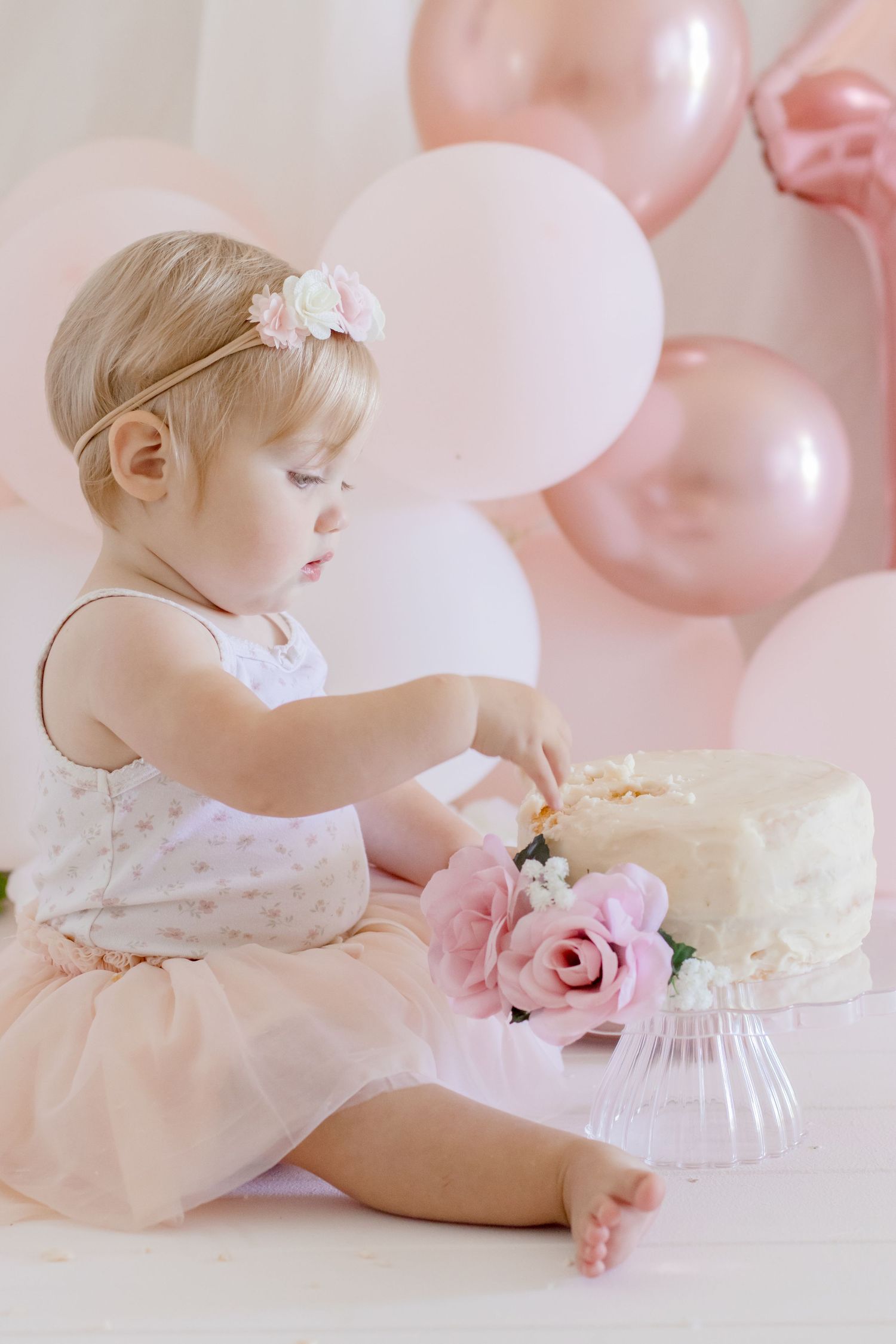 A soft pink birthday scene with white cake, rose decorations, and delicate tulle dress.