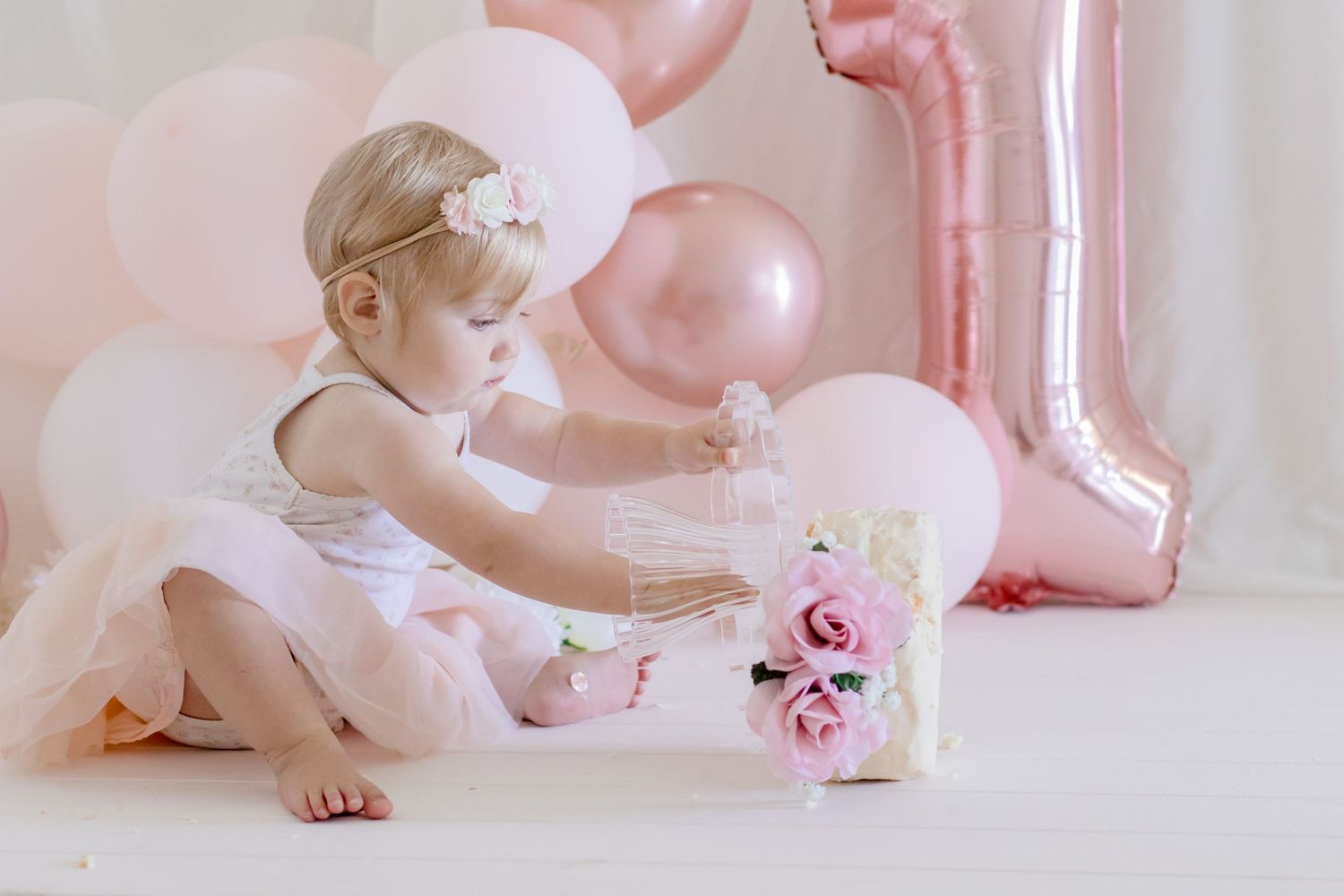 Celebratory scene with tulle dress, pink balloons and roses for first birthday photoshoot.