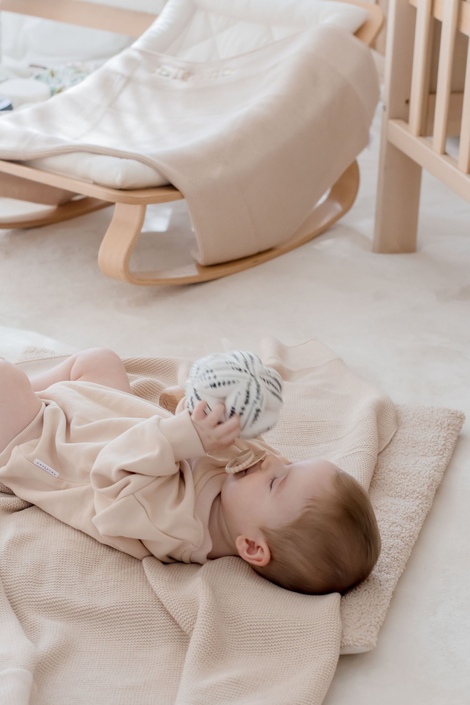 Peaceful nursery scene with soft textured blankets and cushions arranged on light wooden furniture.