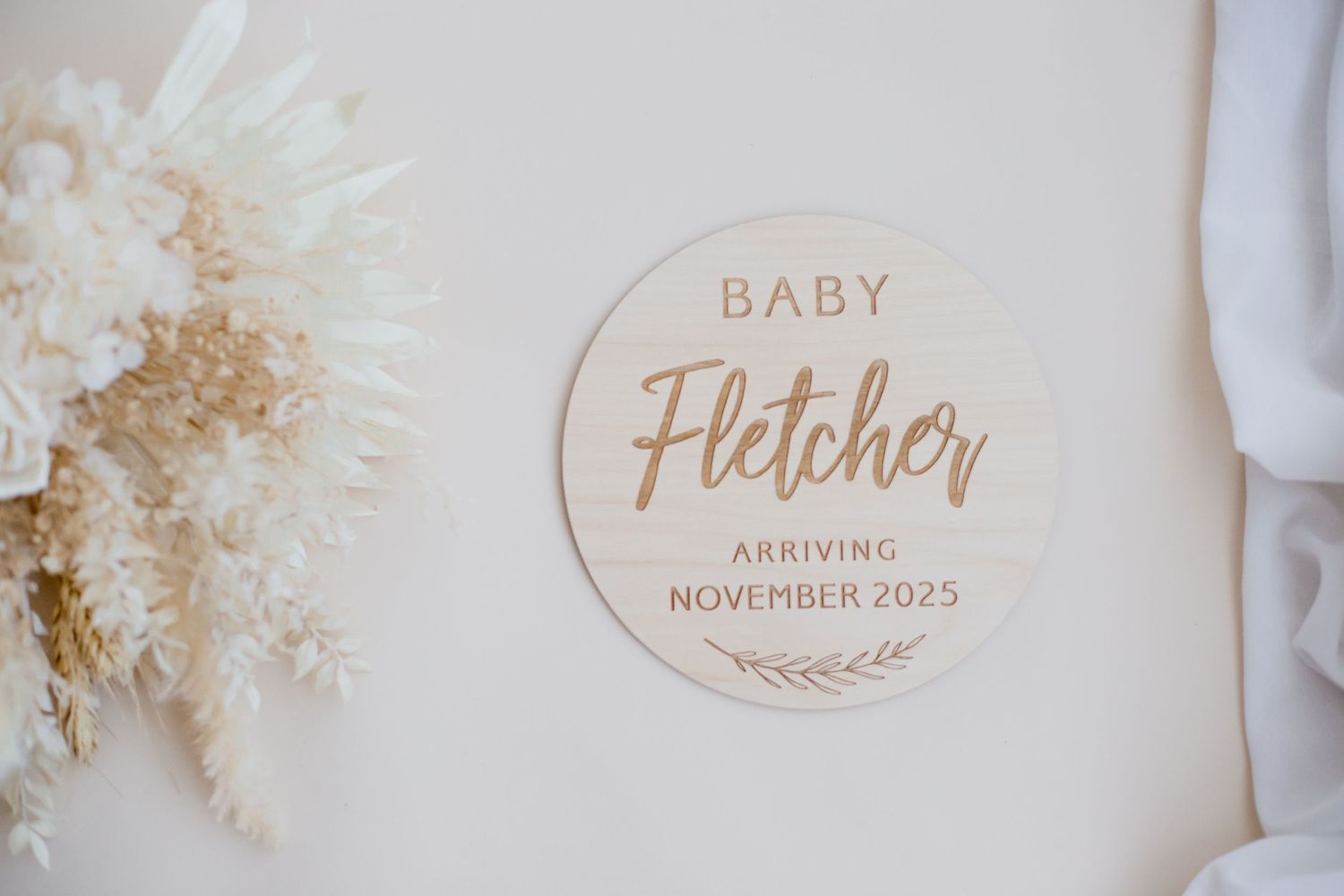 Circular wooden announcement sign for Baby Fletcher arriving November 2025.