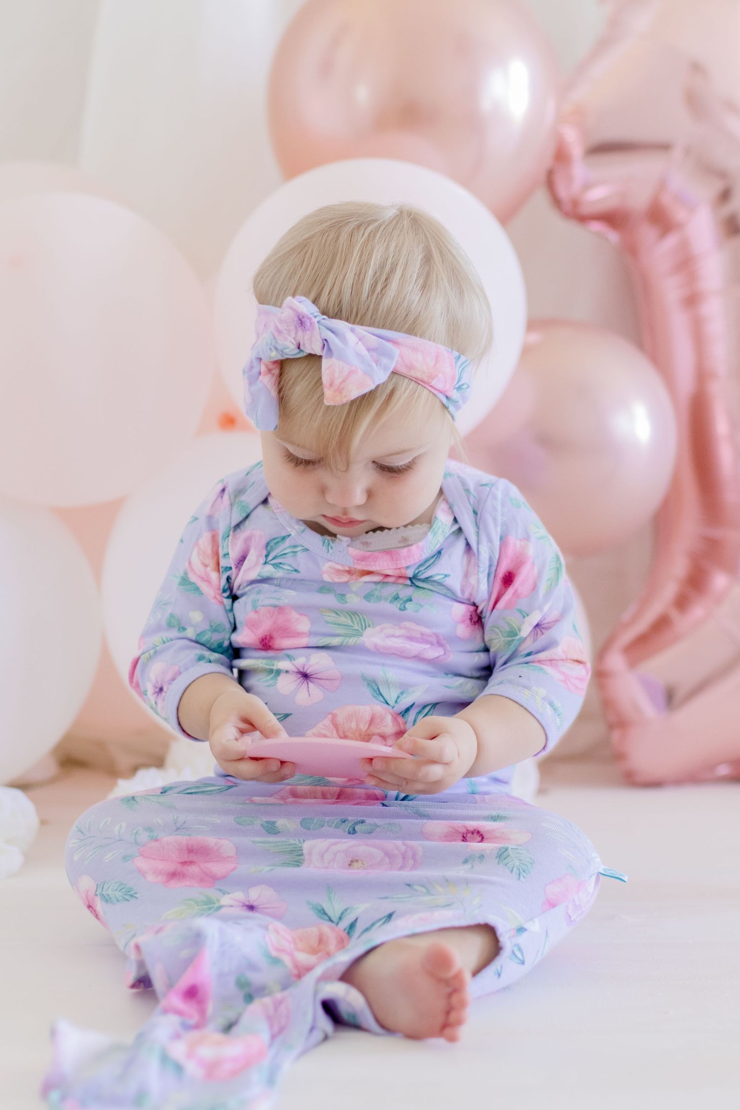 A pastel floral outfit matches perfectly with rose gold balloons in a gentle studio scene.
