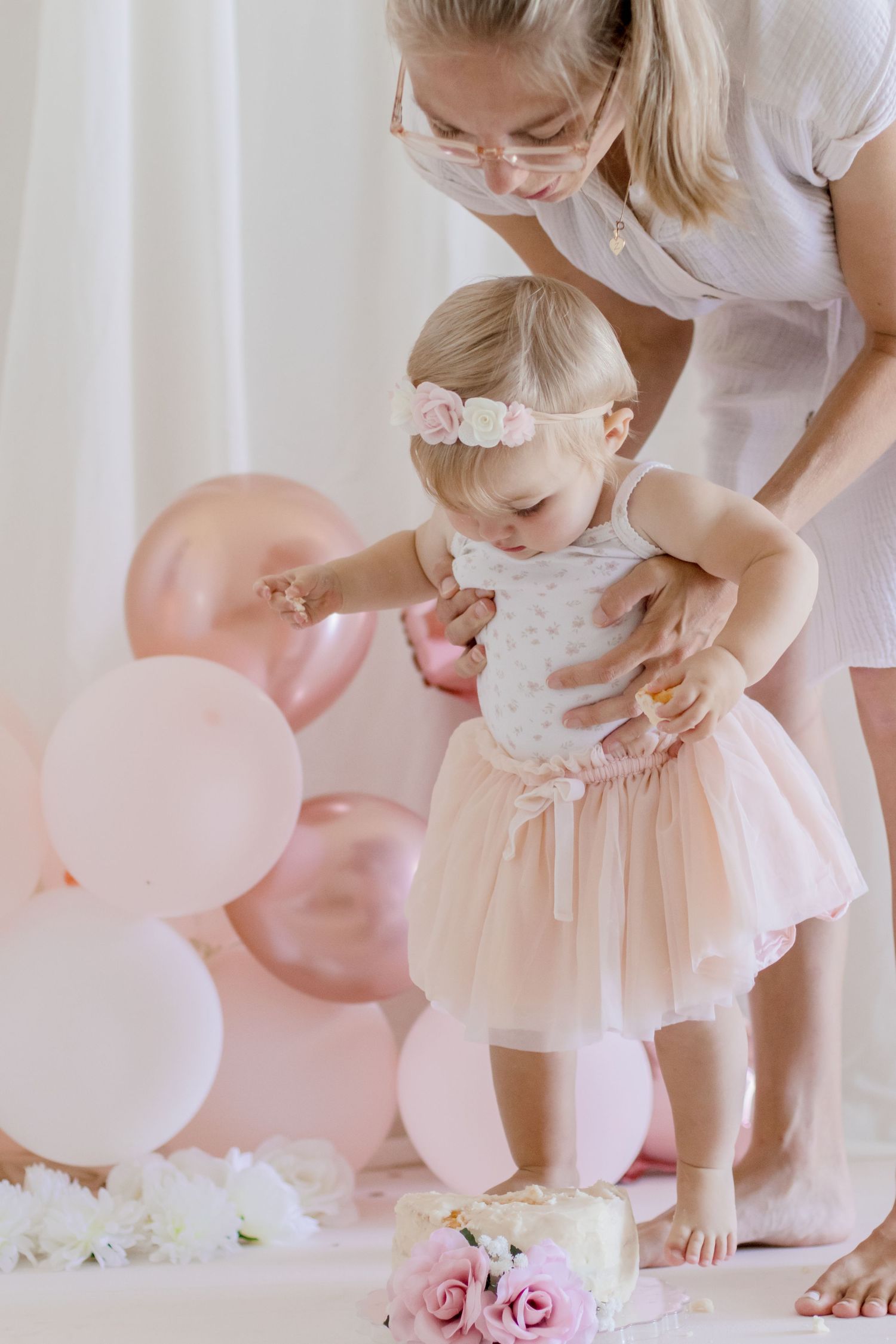 A delicate pink celebration scene with tulle dress, balloons and roses in soft lighting.