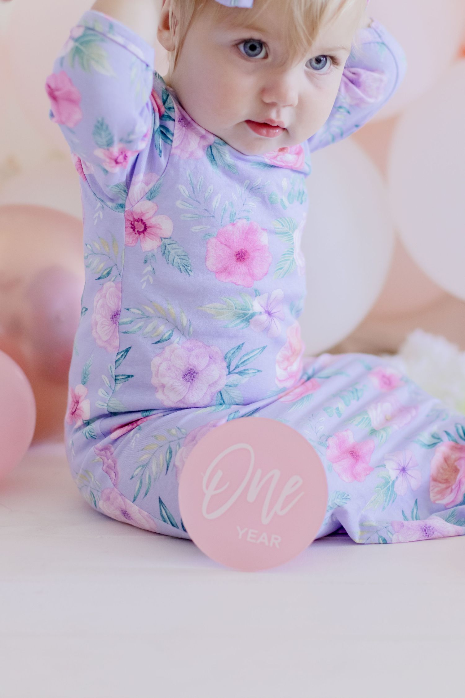 Close-up of floral print baby clothes with pink circular logo detail.