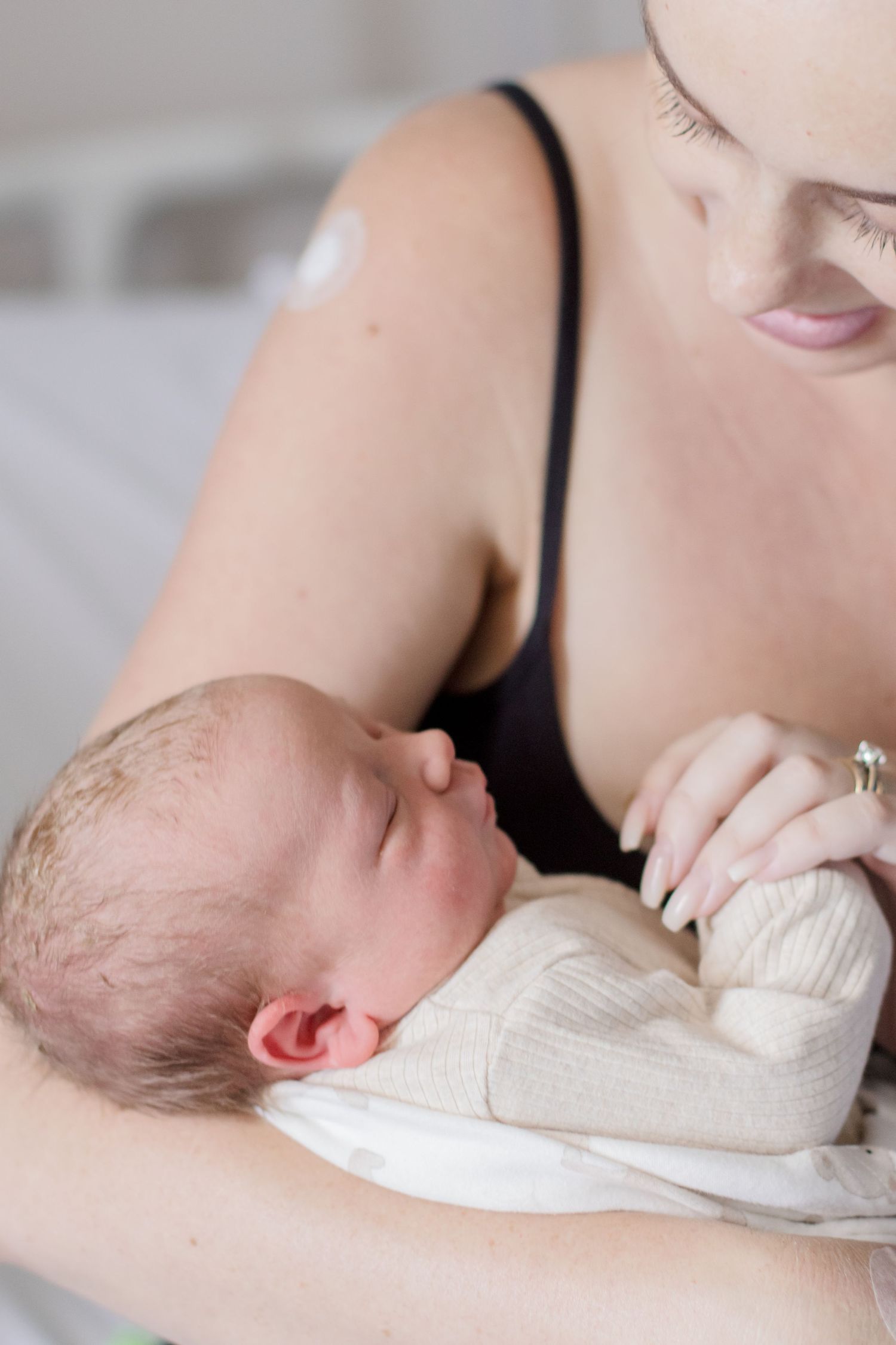 Tender moment of newborn in white clothing resting peacefully.