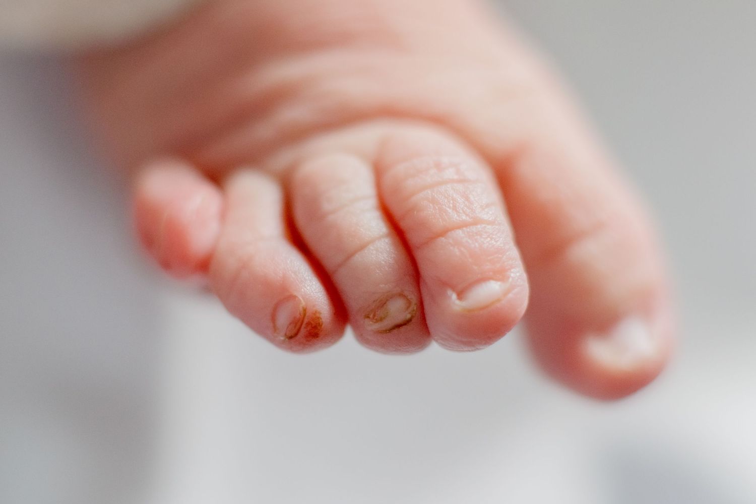 Close-up of tiny newborn baby fingers with delicate wrinkled skin and soft details.