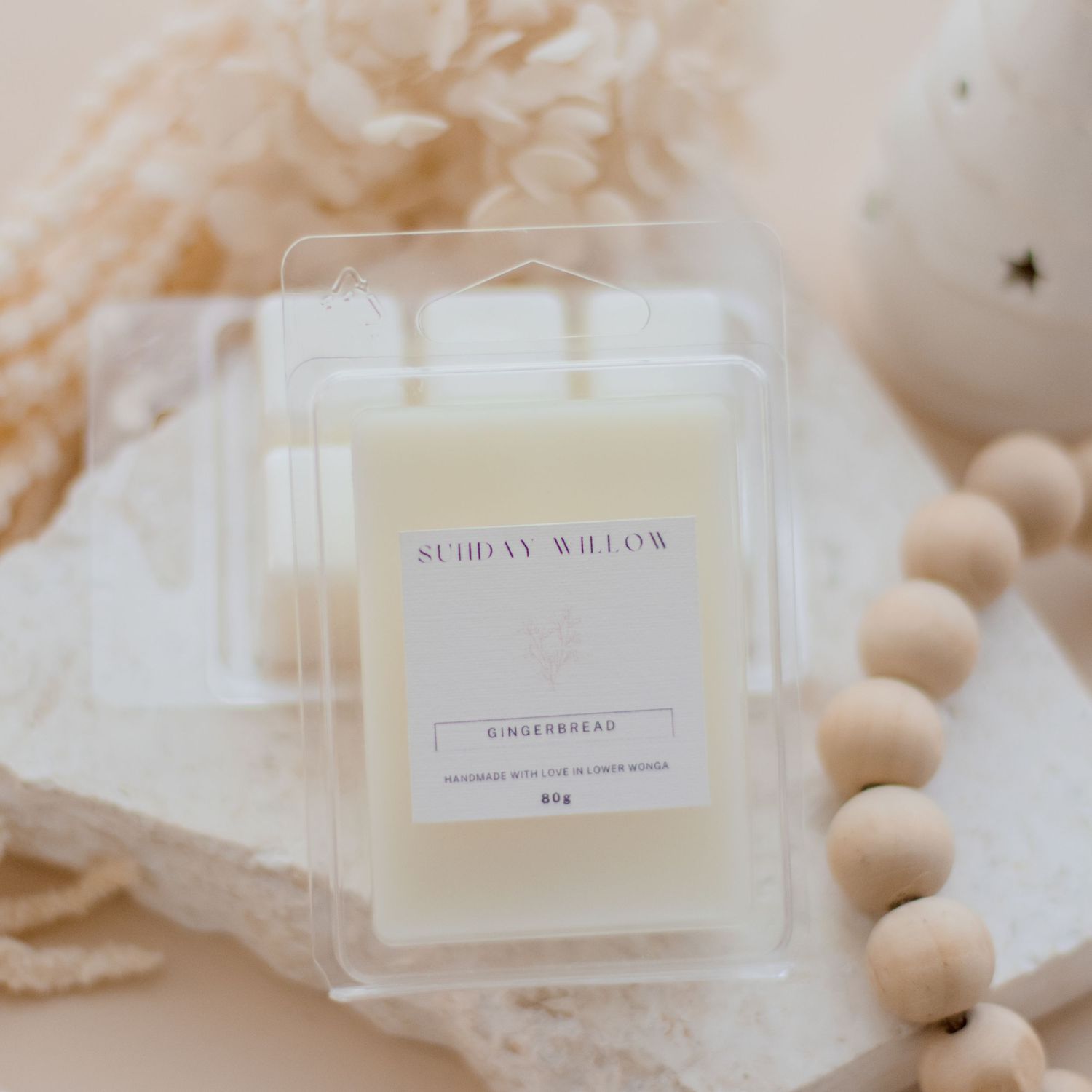 Sunday Willow scented candle in clear acrylic packaging with wooden beads.