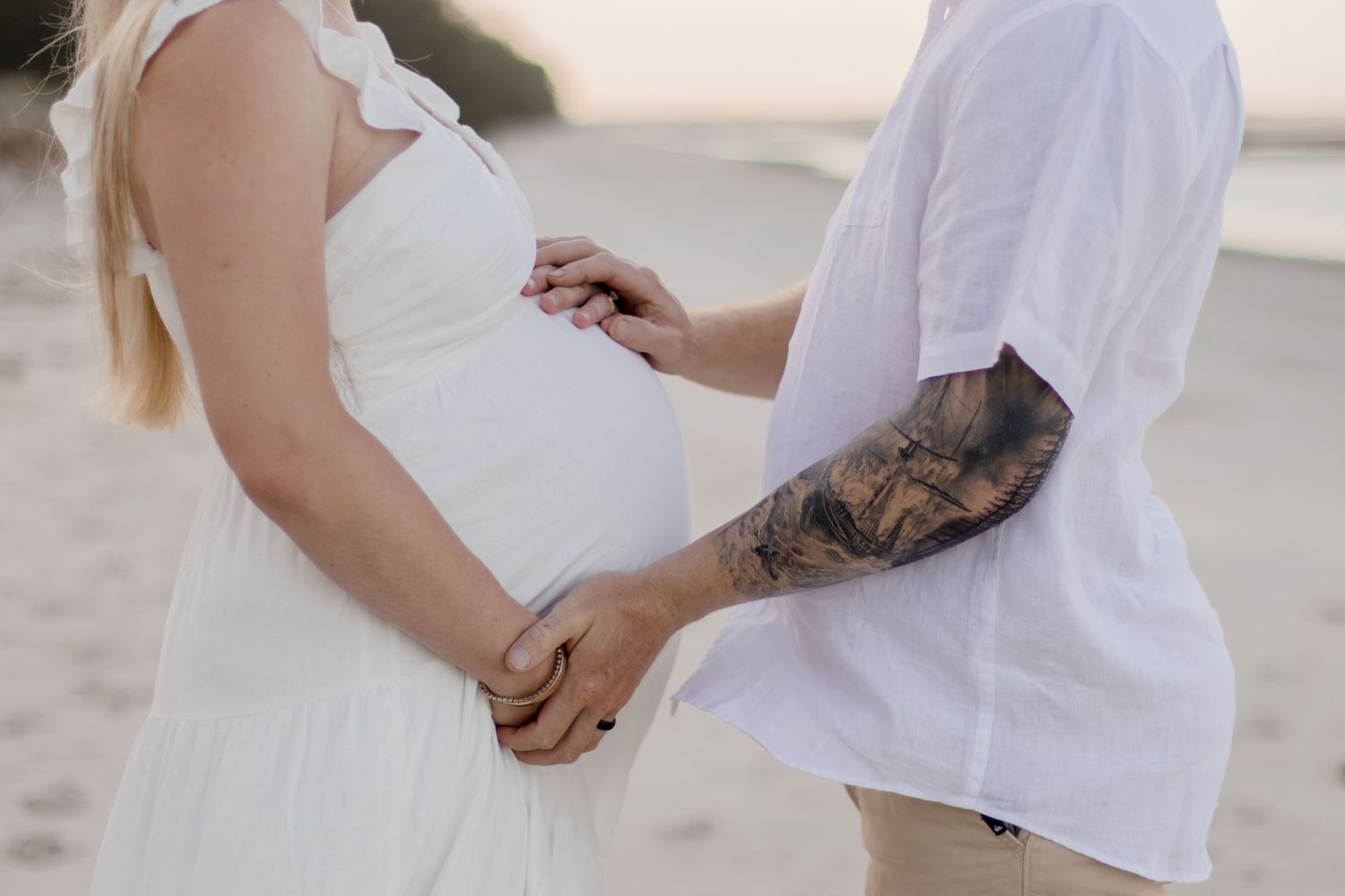 Detail shot of a couple holding hands during their beachside maternity session.