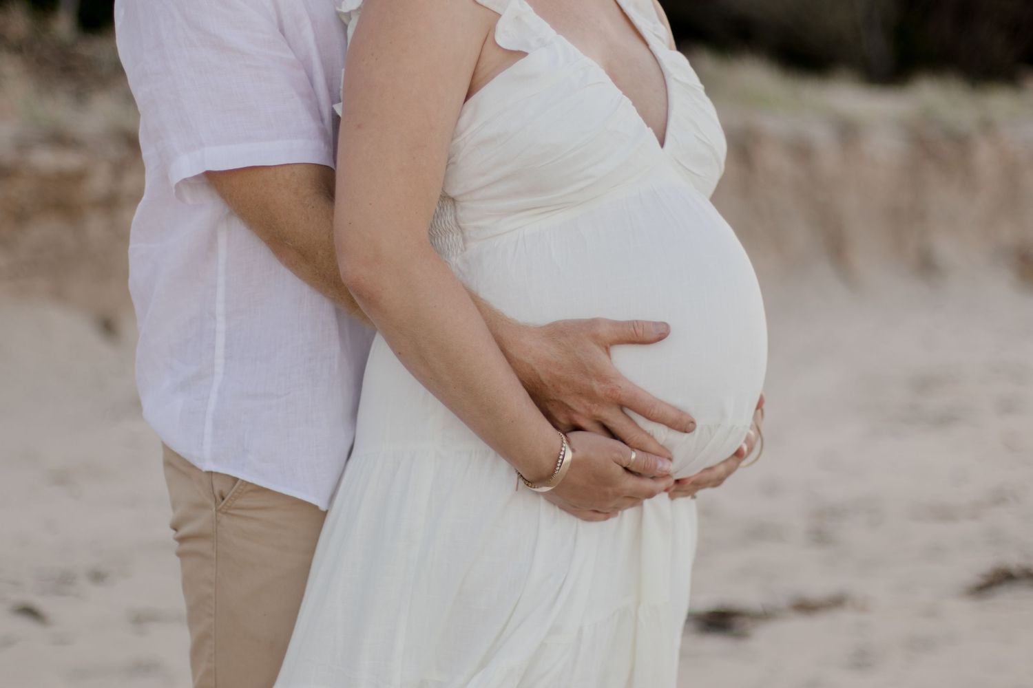 Close-up of expecting parents sharing an intimate moment on the beach.