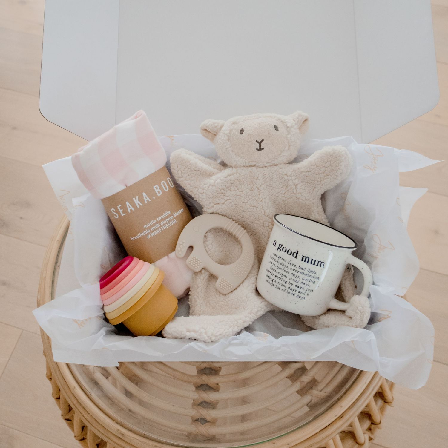 Gift basket with stuffed bear, teething toys and baby products in woven container.
