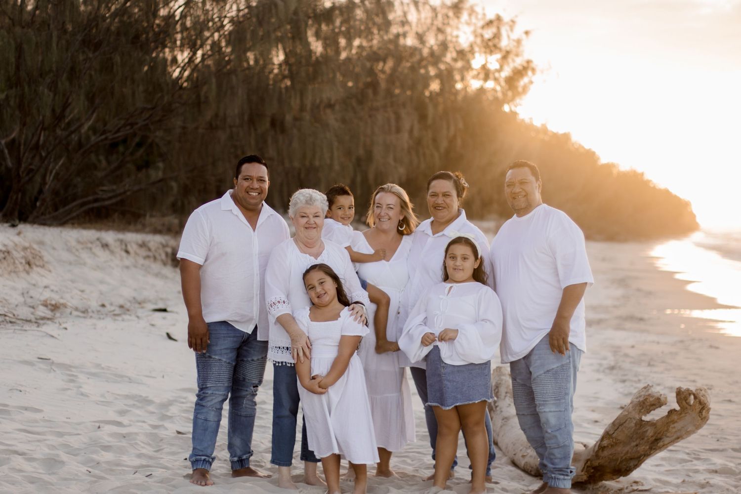 Multiple candid photos of a family group laughing and embracing on a sandy beach at sunset.