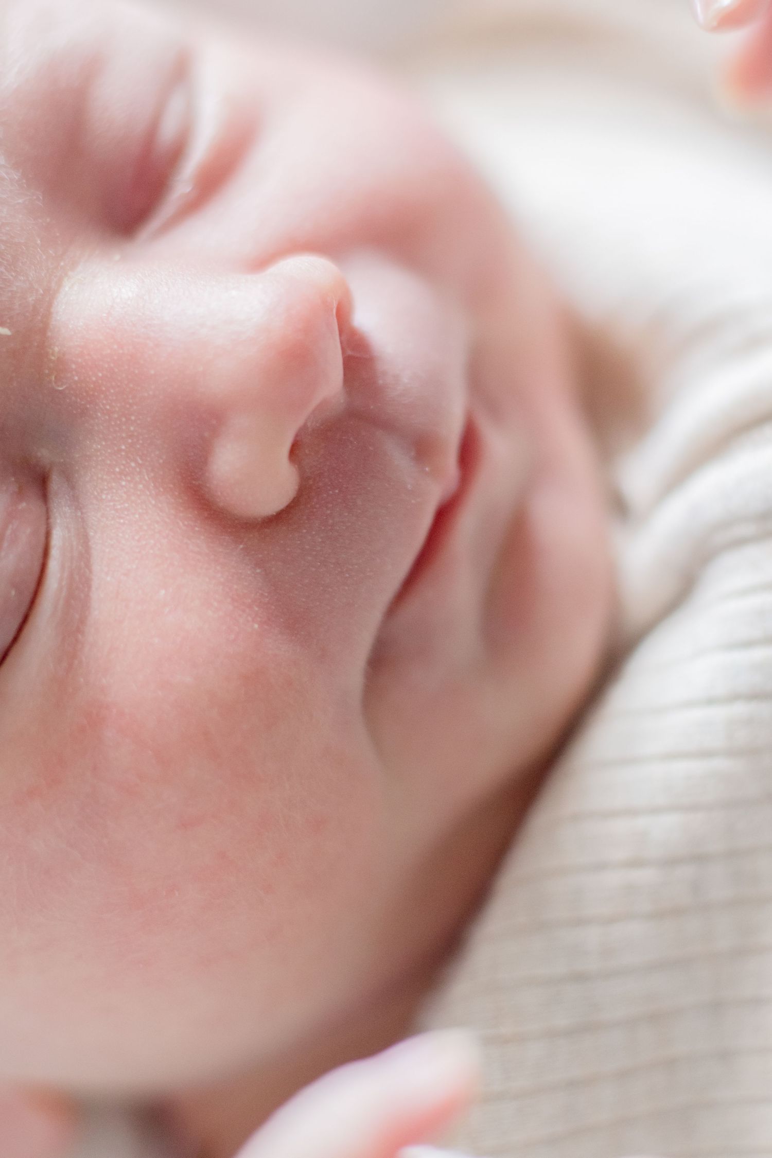 Peaceful sleeping newborn with soft rosy skin in gentle lighting.