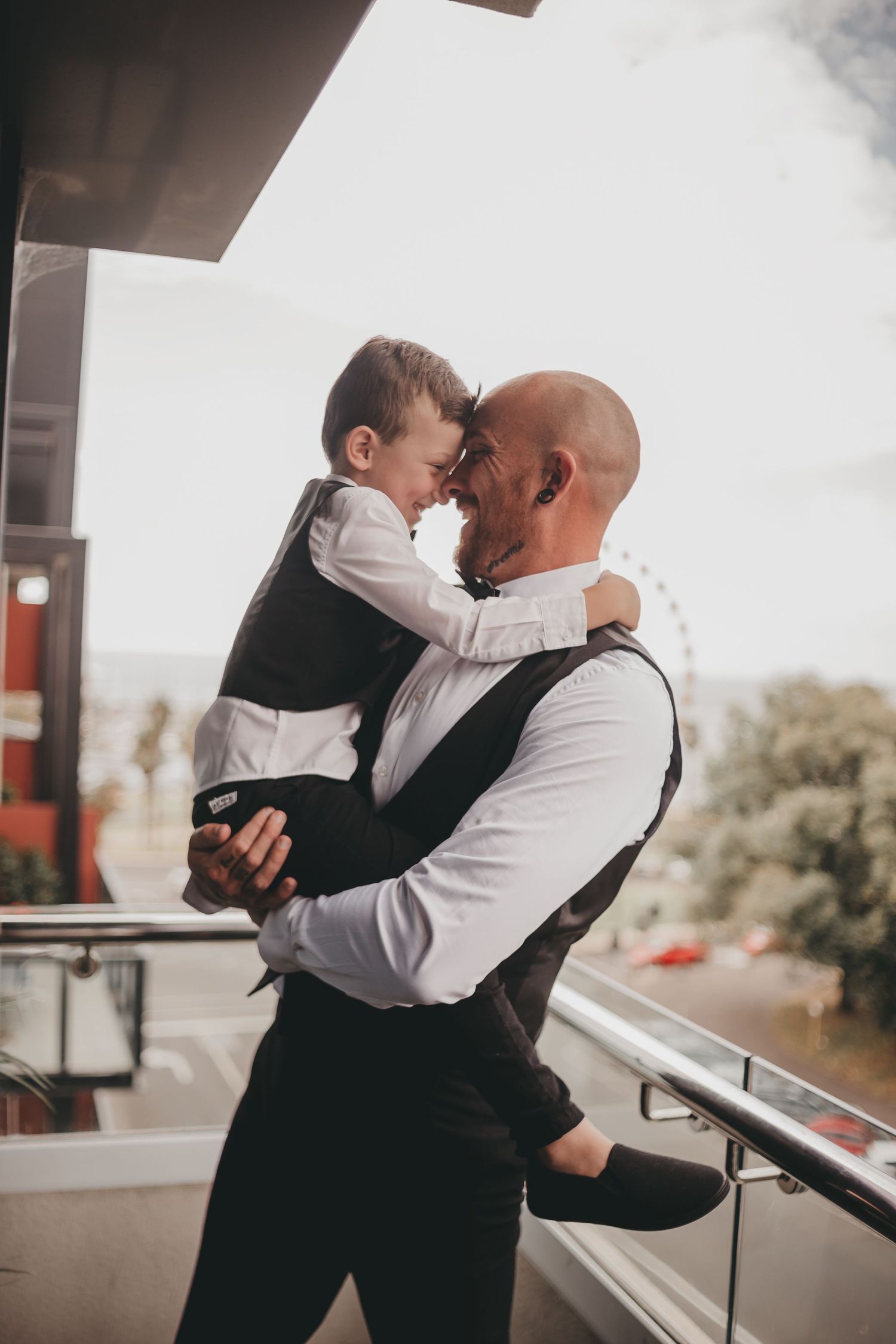 A tender moment on a porch shows two people in formal attire sharing a loving embrace.