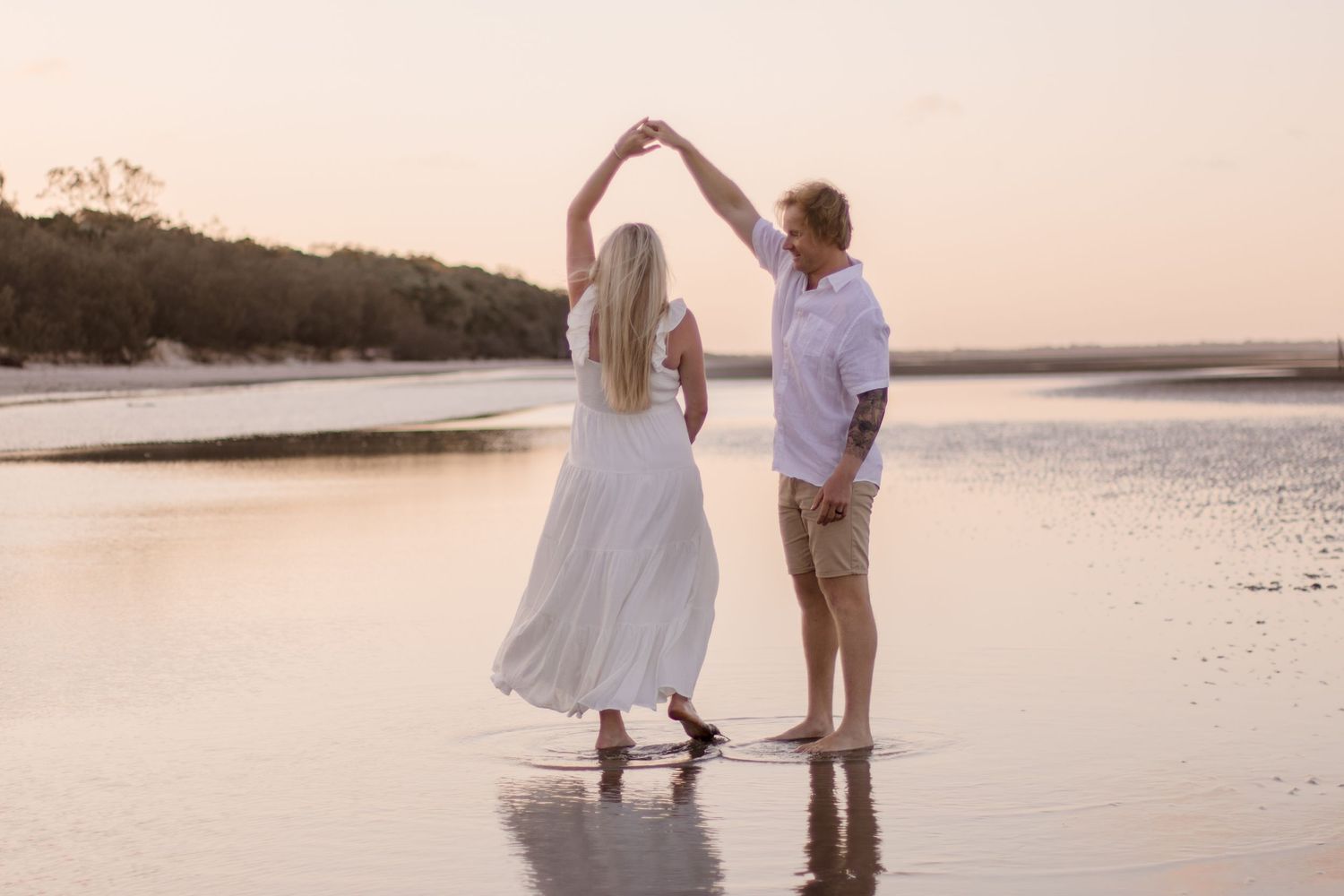 A couple dances on the beach during their sunset maternity photoshoot.