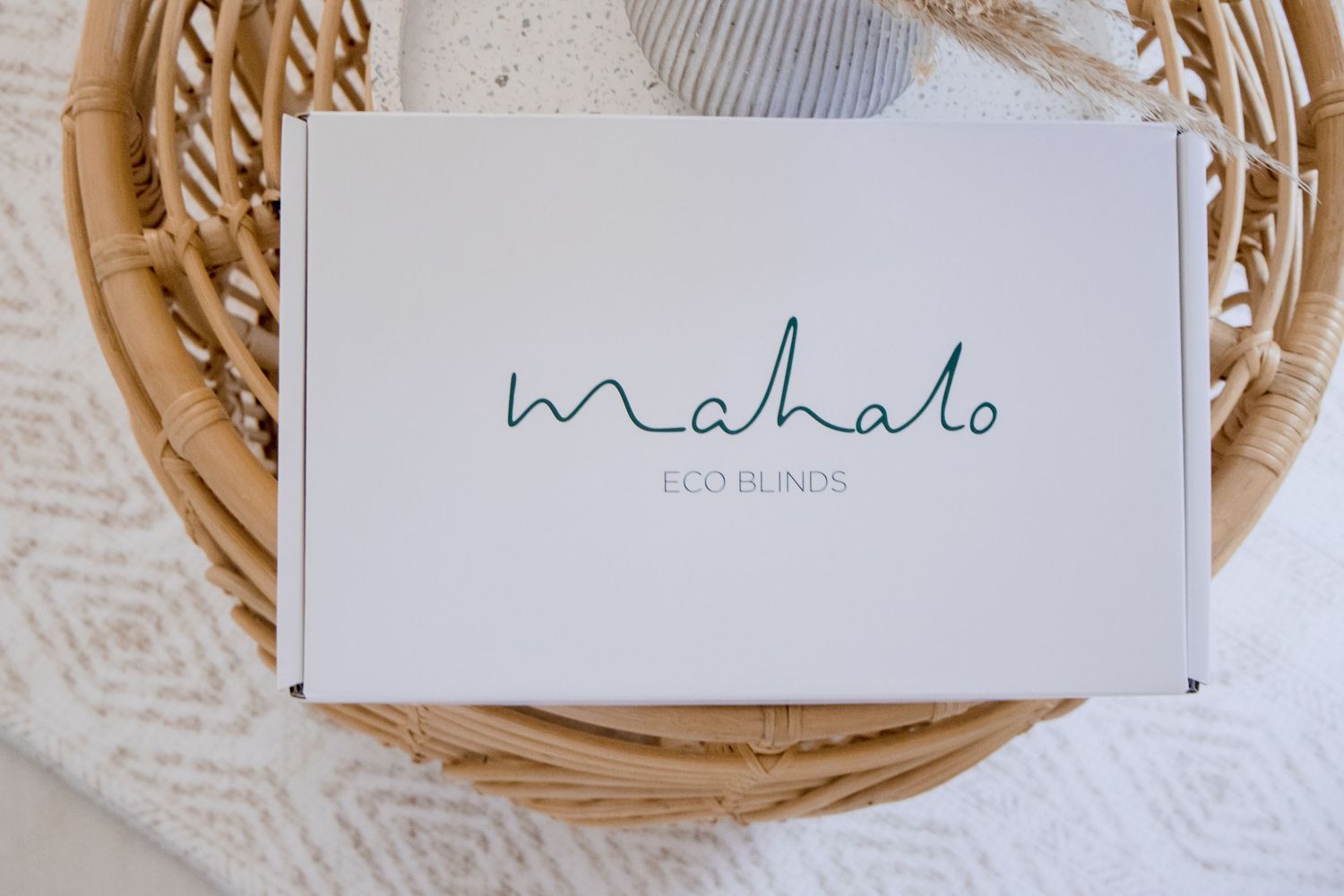 White box with 'Mahalo' text in green script on woven rattan surface.