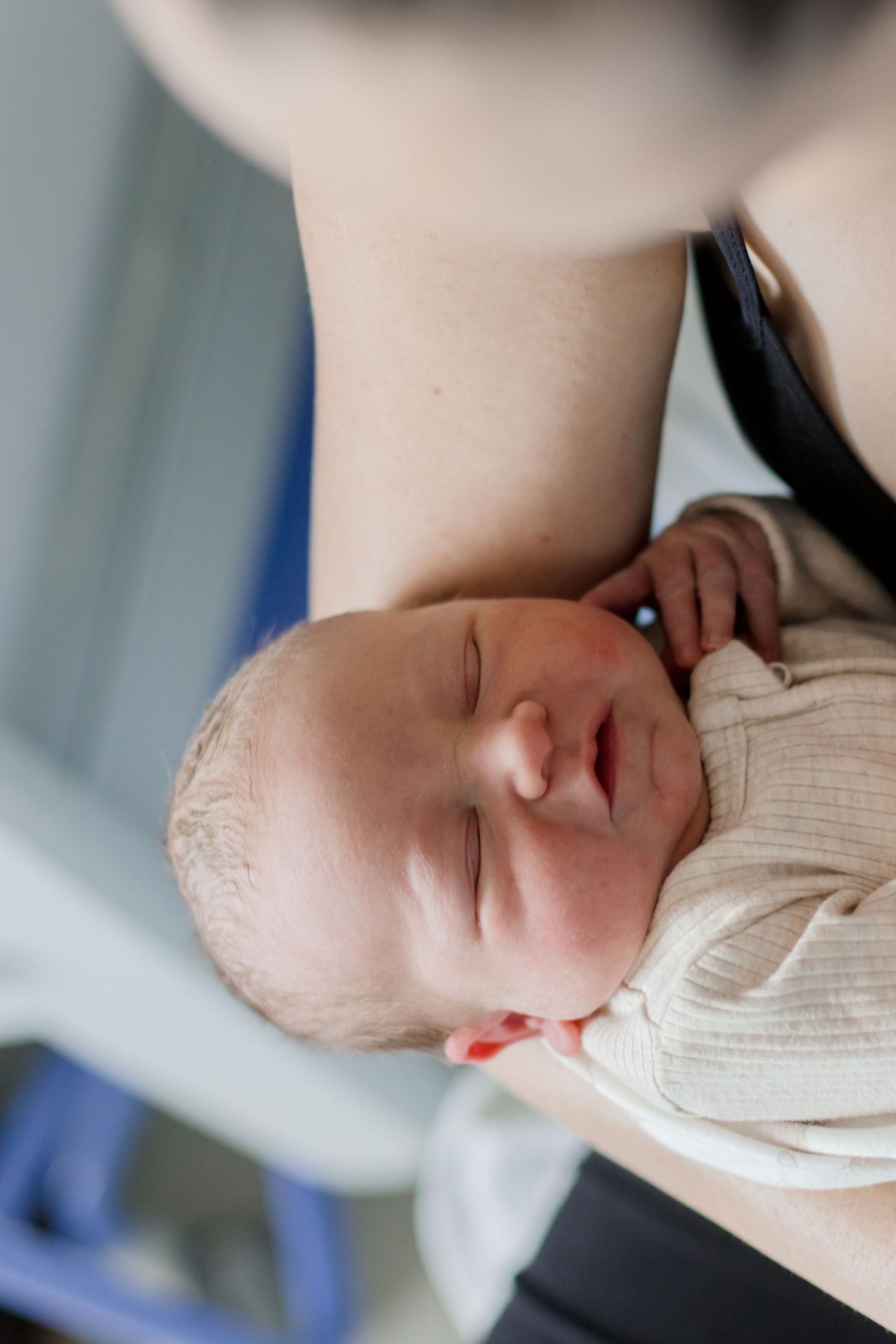 Peaceful sleeping newborn in cream sweater against soft lighting.