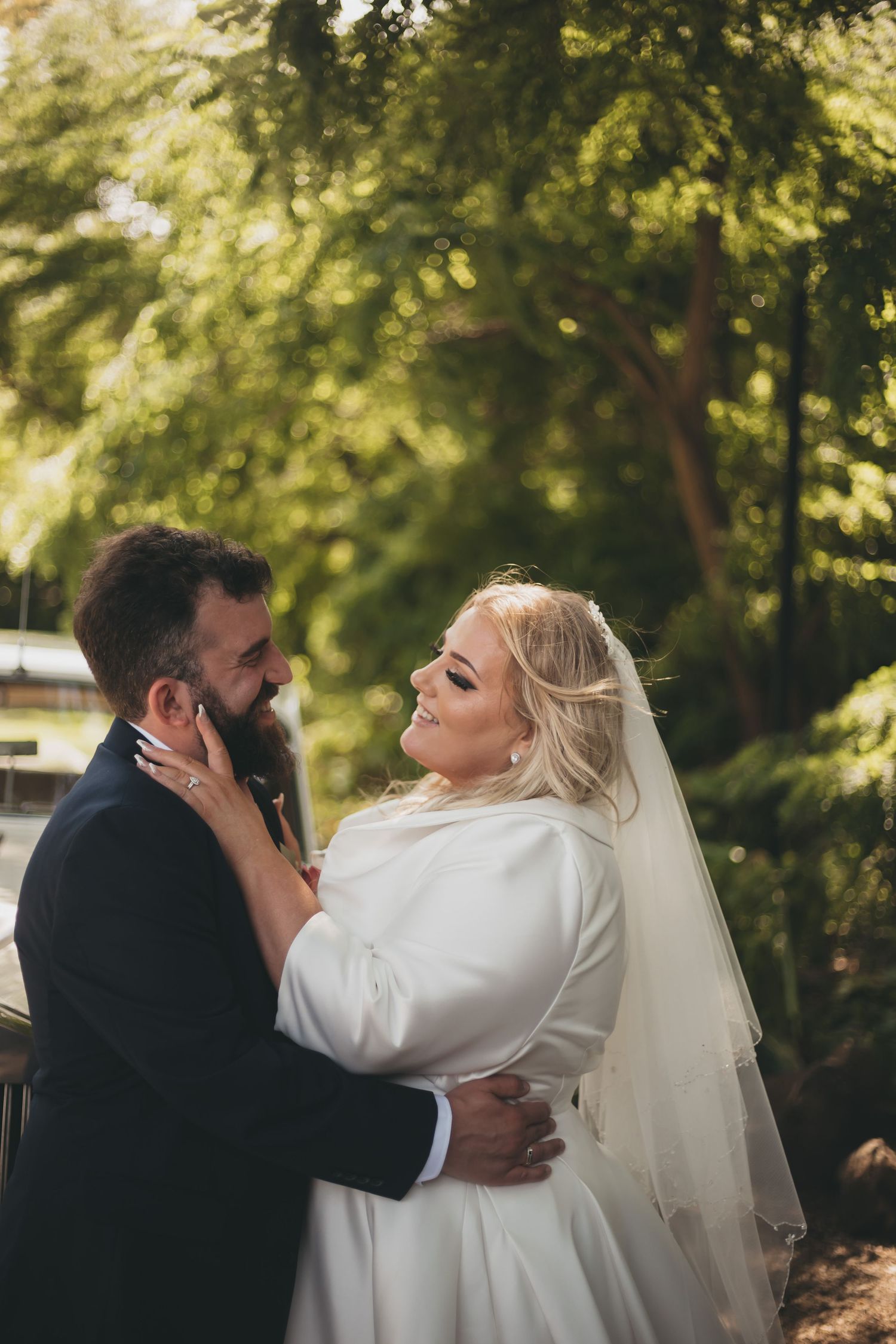 A romantic wedding moment in a garden setting with sunlit trees creating a dreamy natural backdrop.