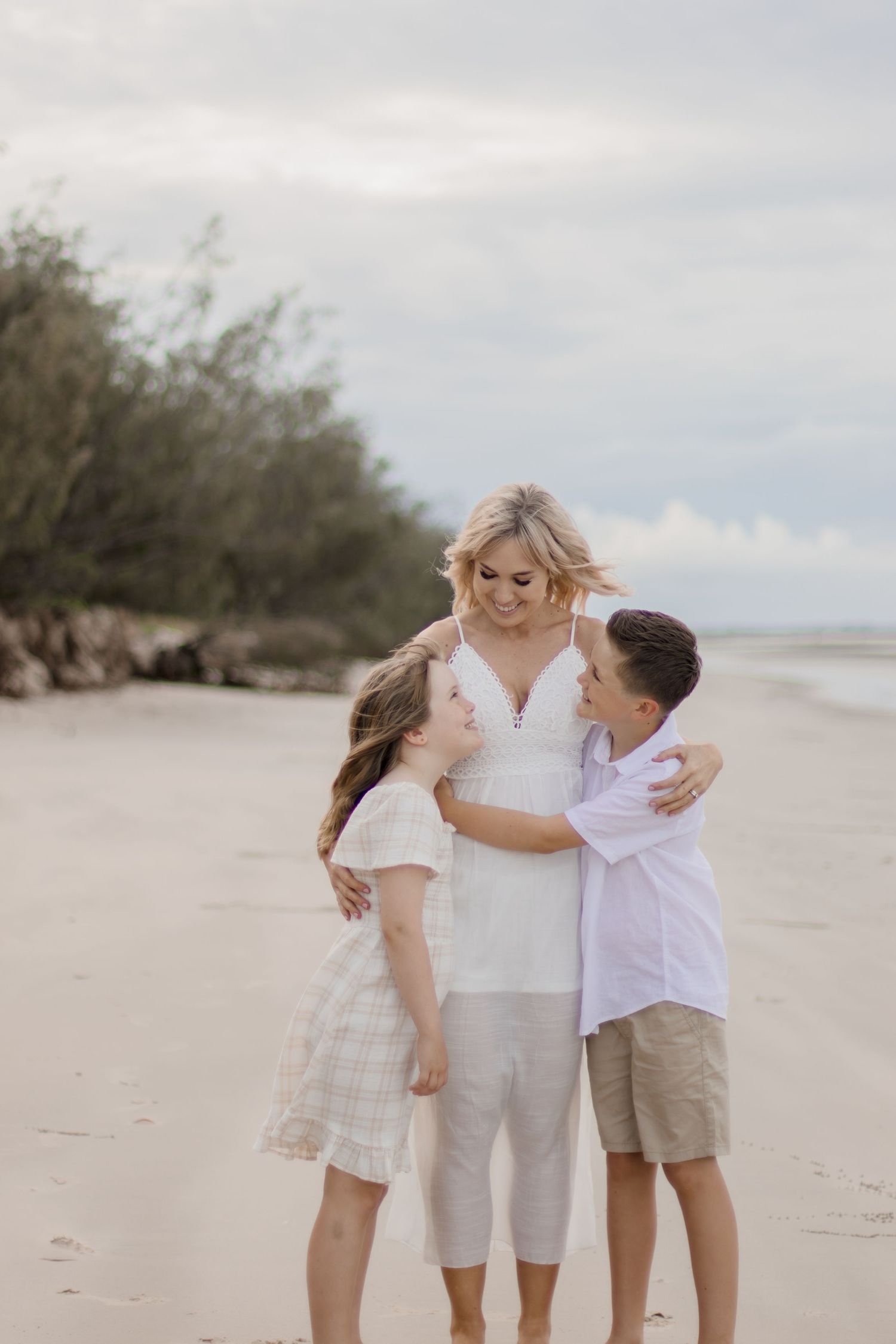 Three people sharing an intimate family moment while embracing on the beach.