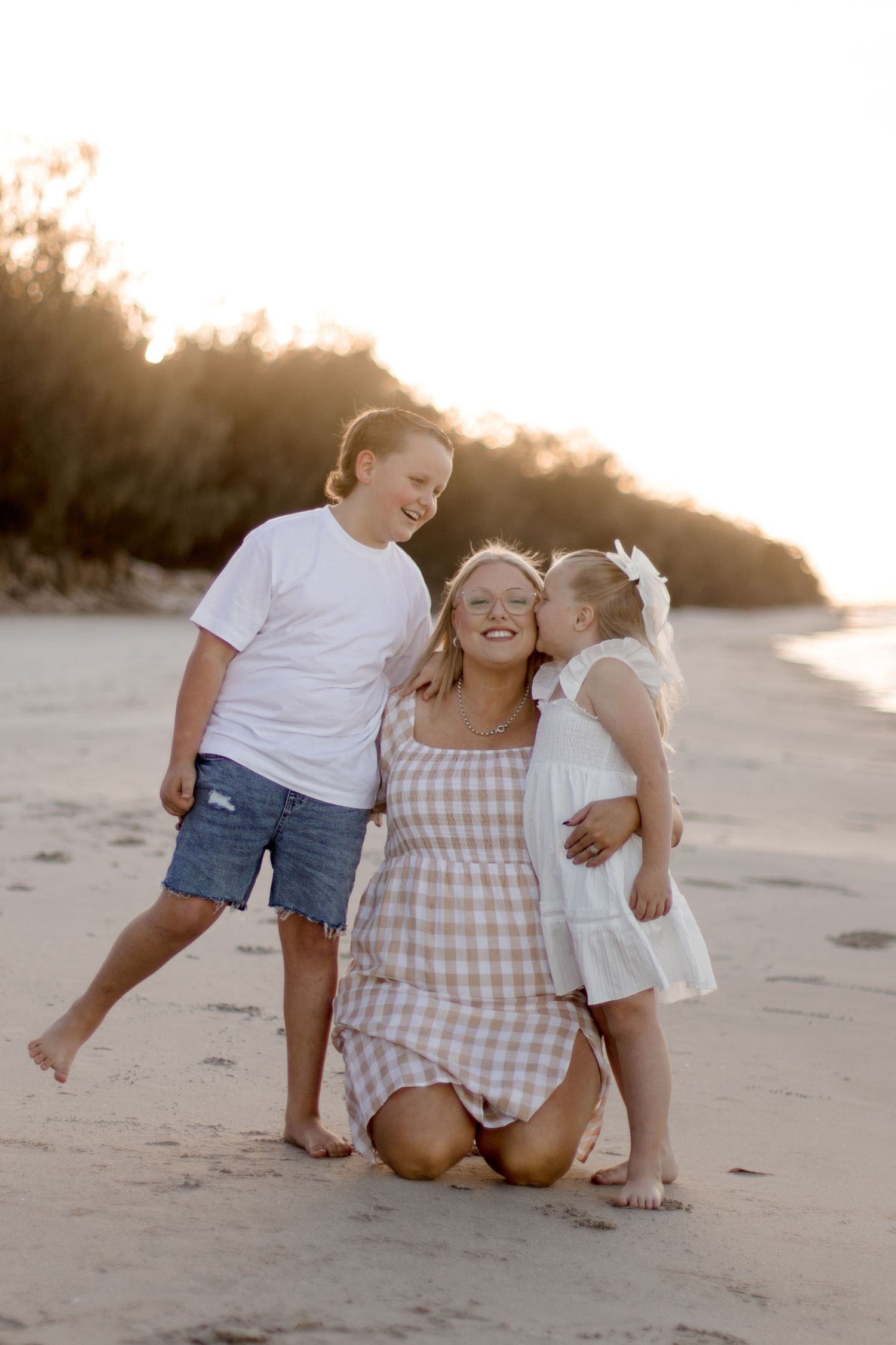 Heartwarming family moment captured at sunset on a sandy beach with laughter and love in warm golden light.