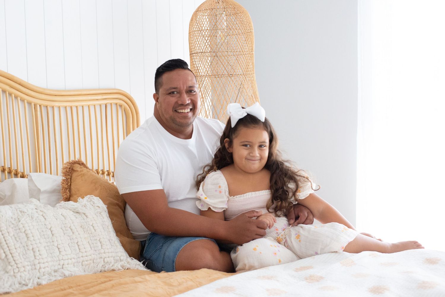Sweet bonding moment captured on beige bed with decorative rattan headboard.