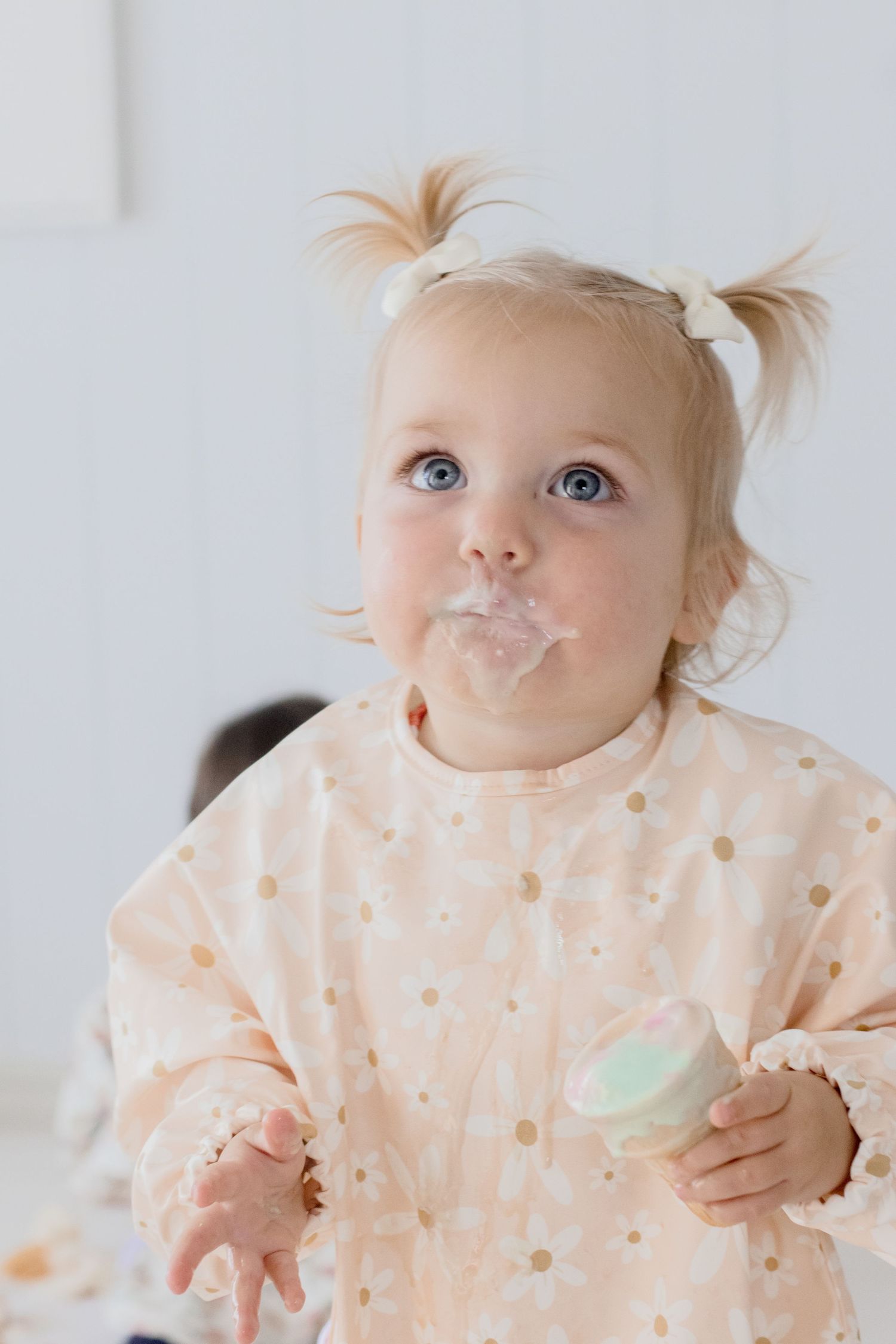 Toddler with pigtails wearing polka dot outfit with messy face.