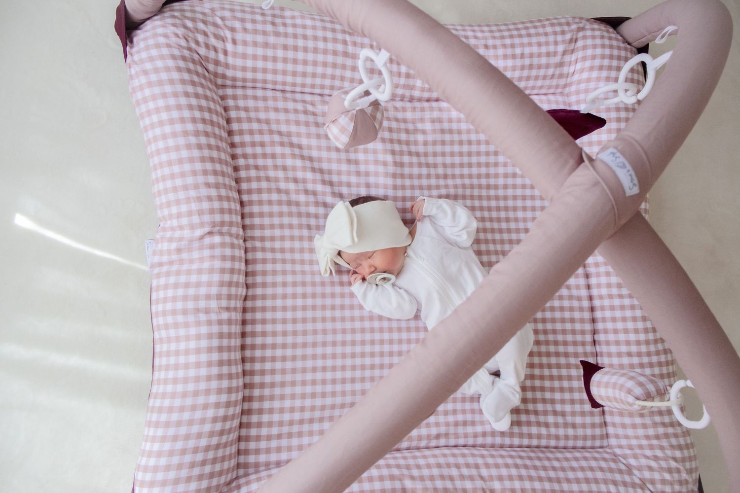 Pink and white gingham bedding with ribbons and delicate fabric ties on a light colored background.