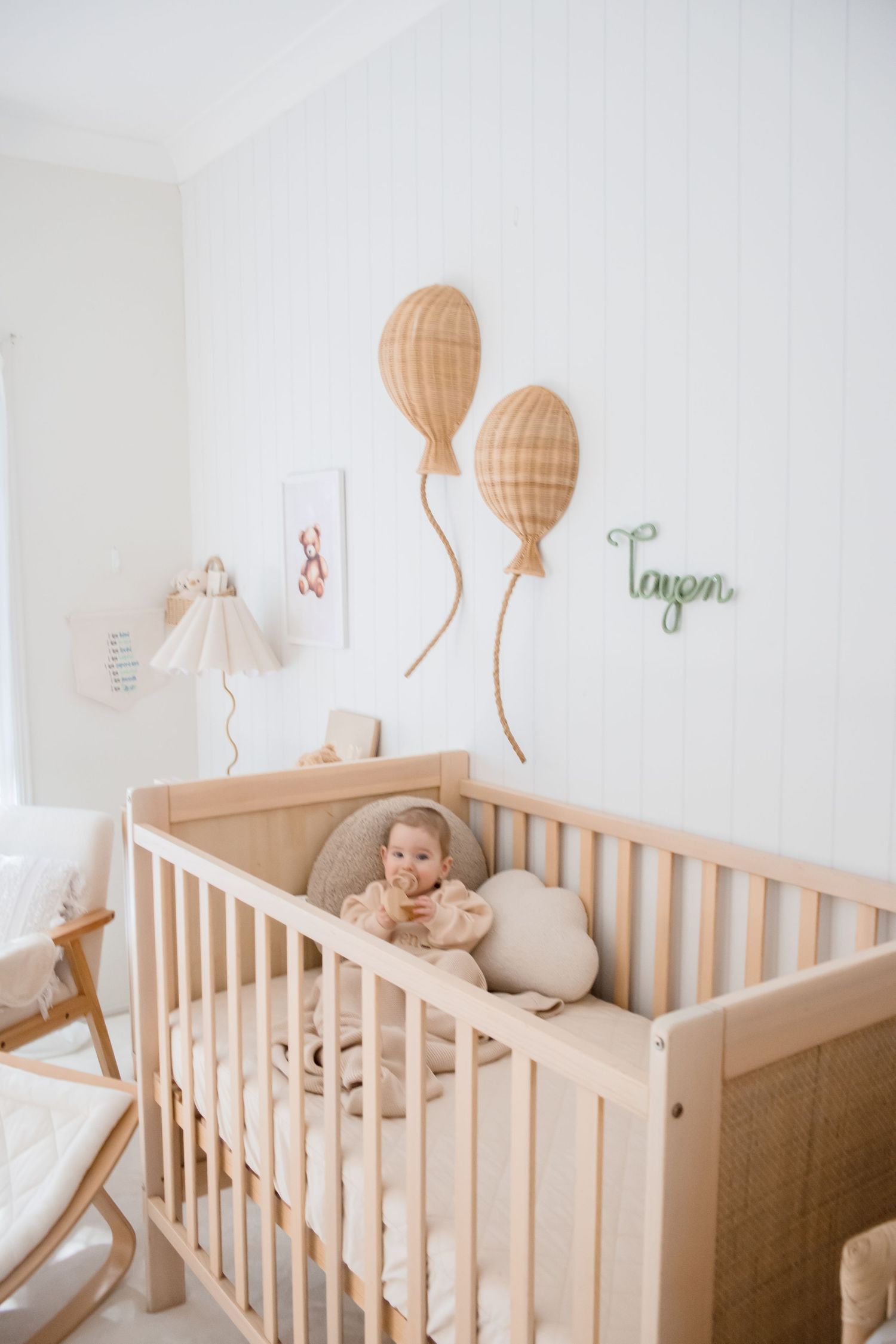 Minimalist nursery with wooden crib and balloon wall decals in neutral tones.