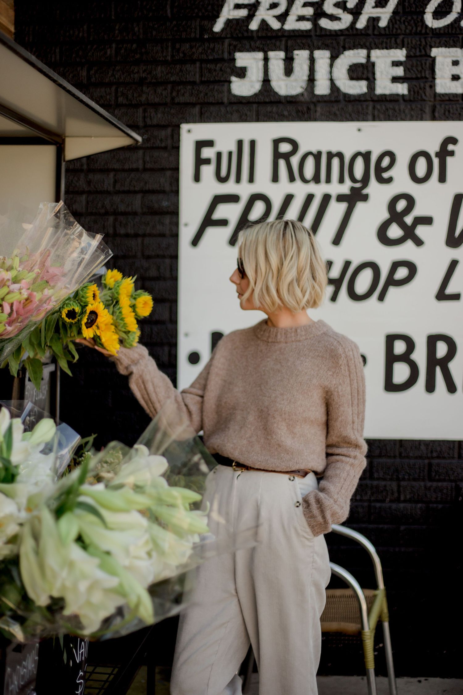 Multiple views of a juice bar interior with black walls featuring menu text and fresh sunflowers in natural lighting.