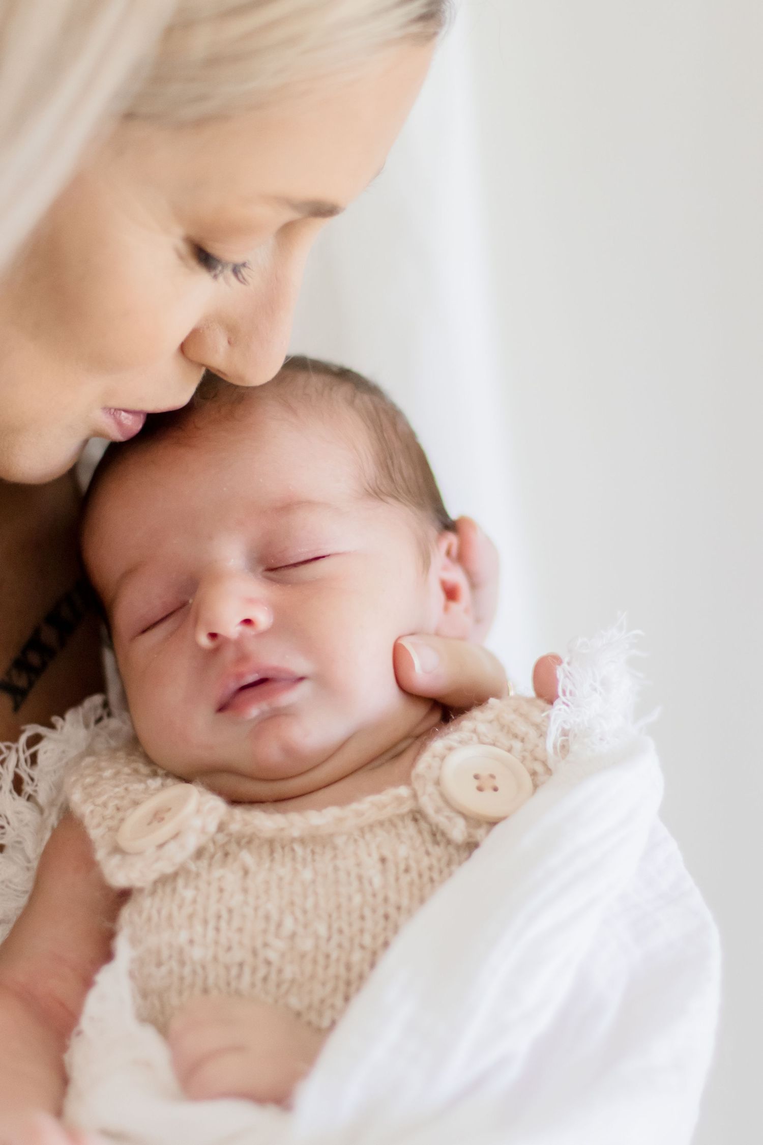 Tender moment captured between mother and sleeping baby in soft natural light.