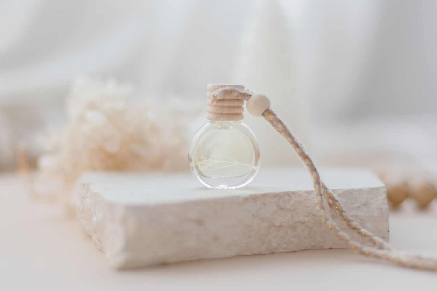 Small glass bottle with twine cord resting on white stone surface.