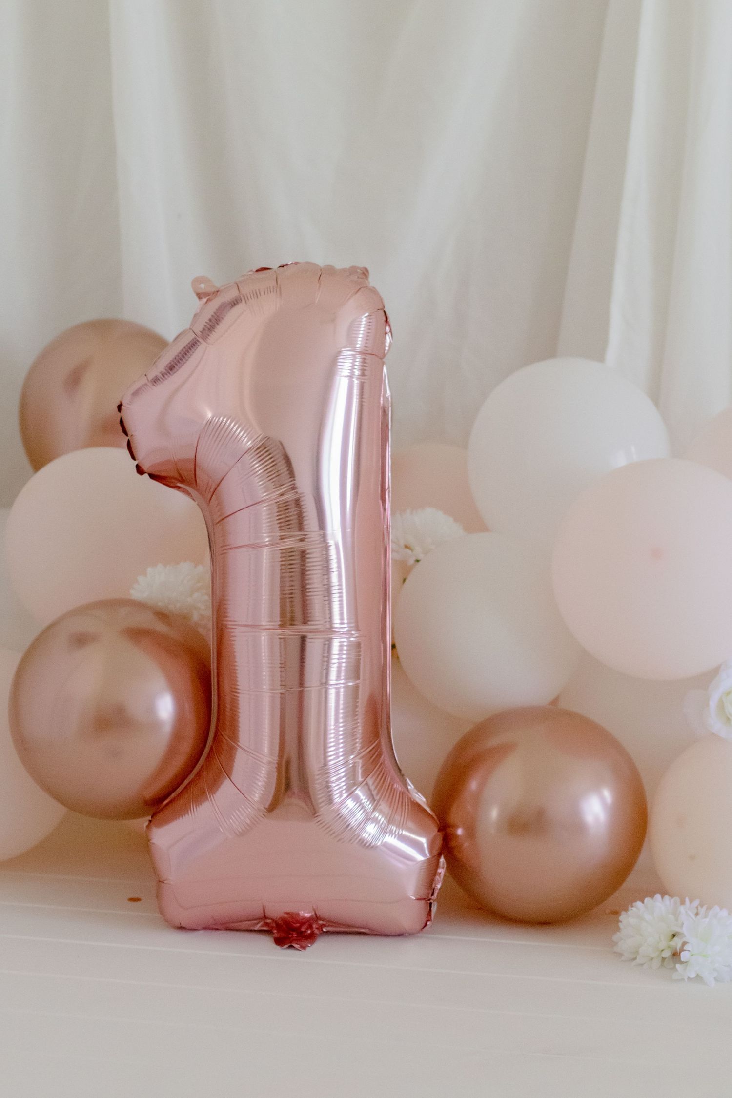 Rose gold number one balloon with pink and white balloon decorations.